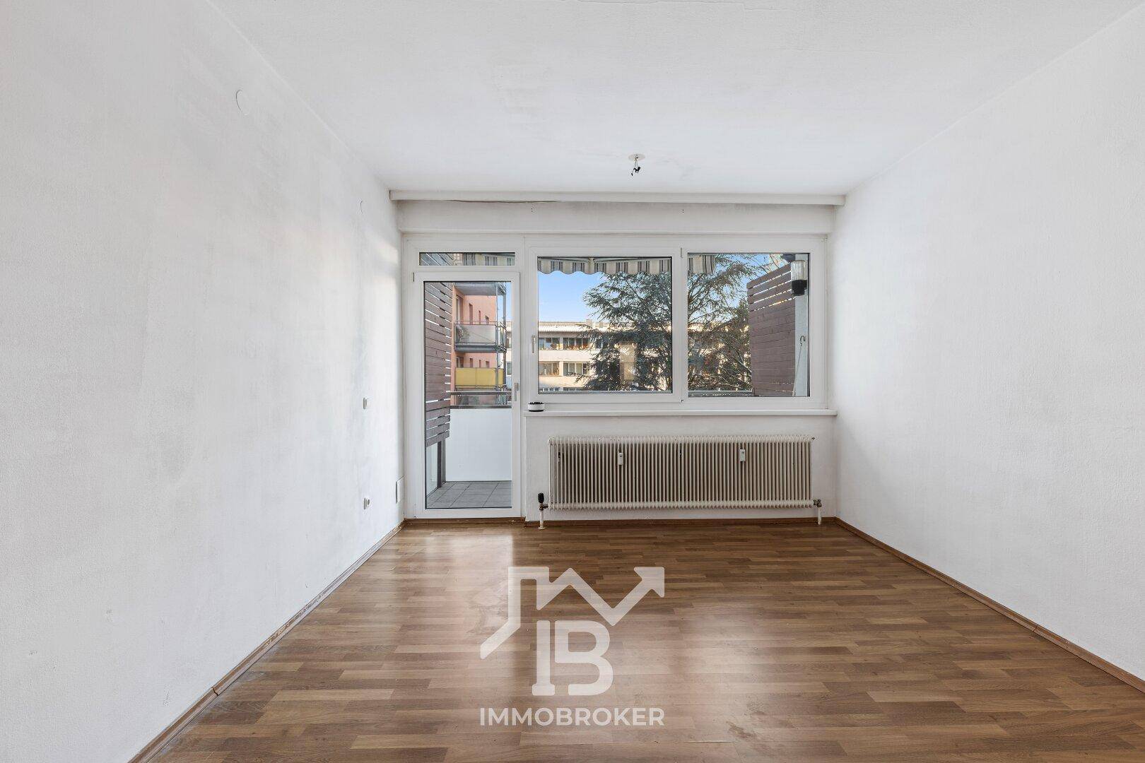 Heller Raum mit Laminatboden und Zugang zu einem Balkon, bietet viel Tageslicht.