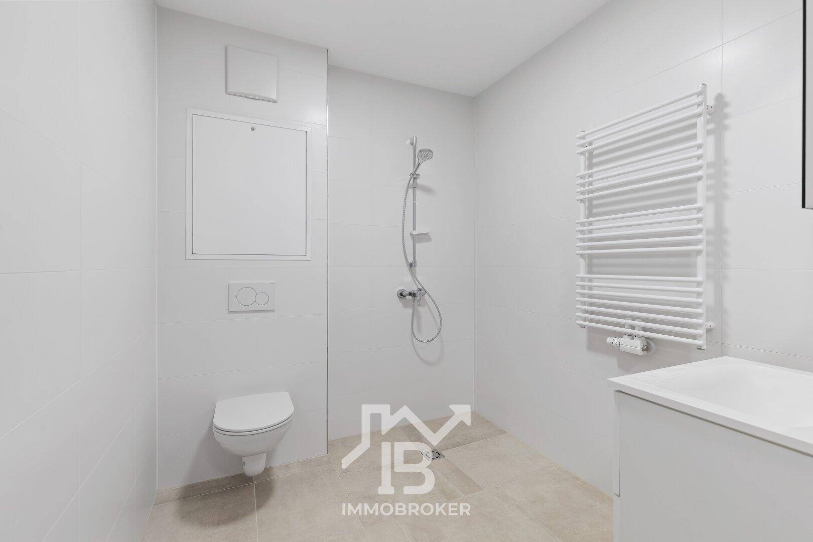 Modernes Badezimmer mit Dusche, wandhängendem WC und Handtuchheizkörper.