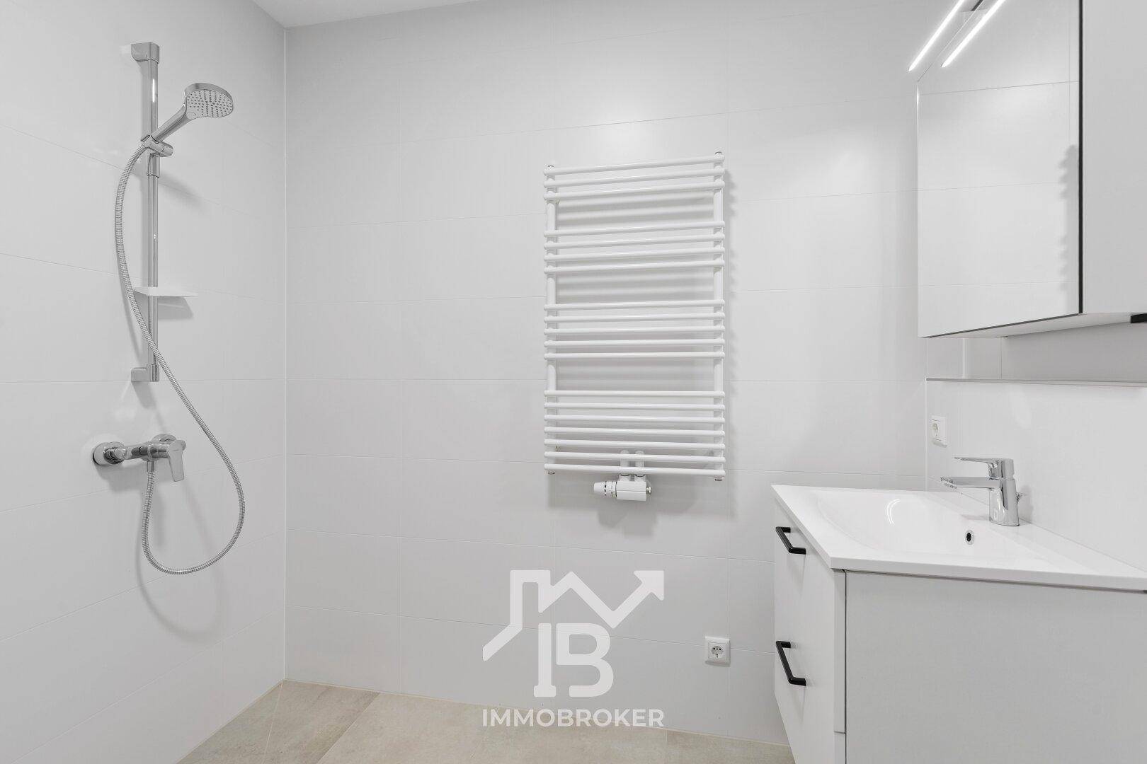 Helles Badezimmer mit Dusche, Waschbecken und Spiegelschrank.
