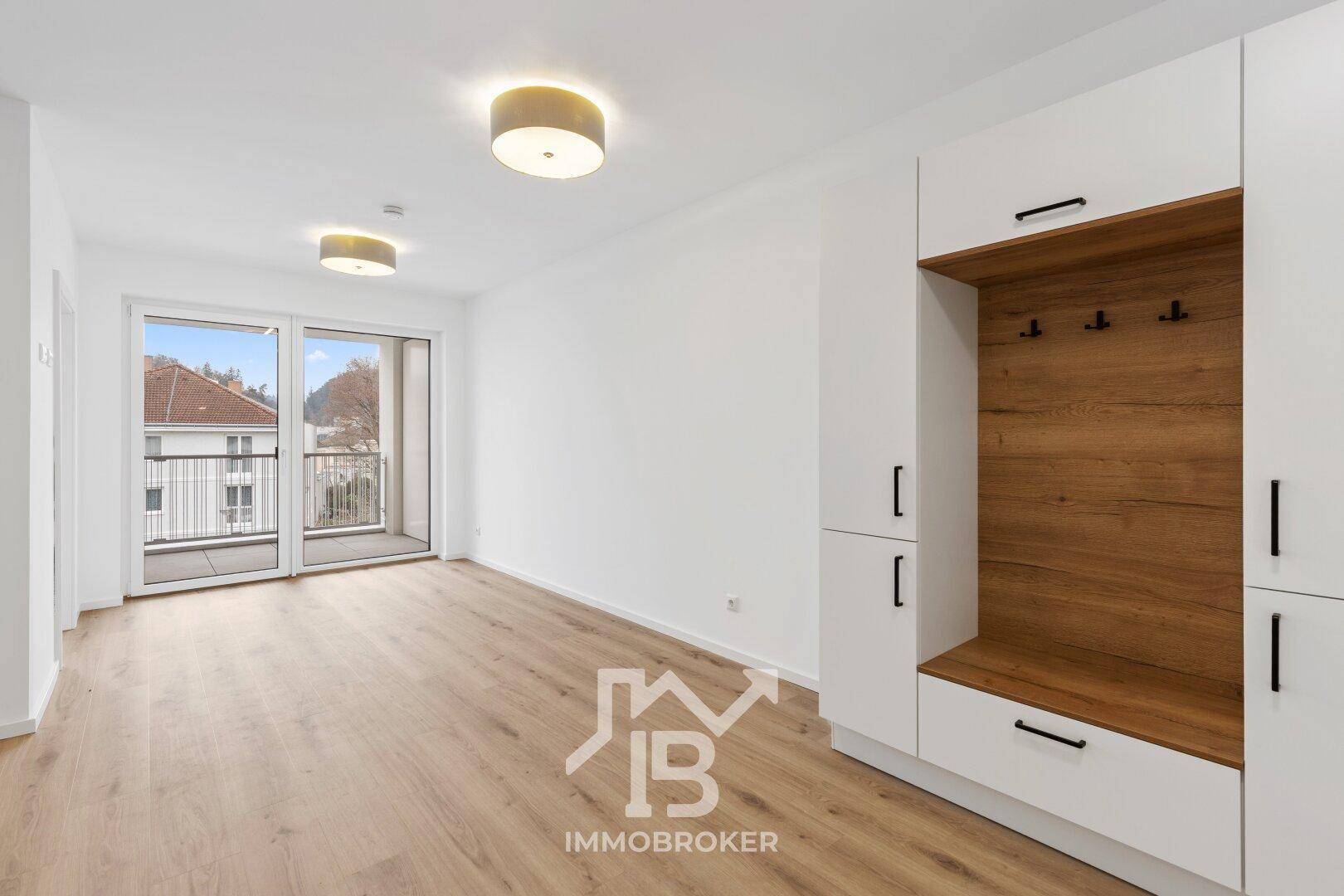 Eingangsbereich mit integrierter Garderobe, Parkettboden und Zugang zum Balkon.