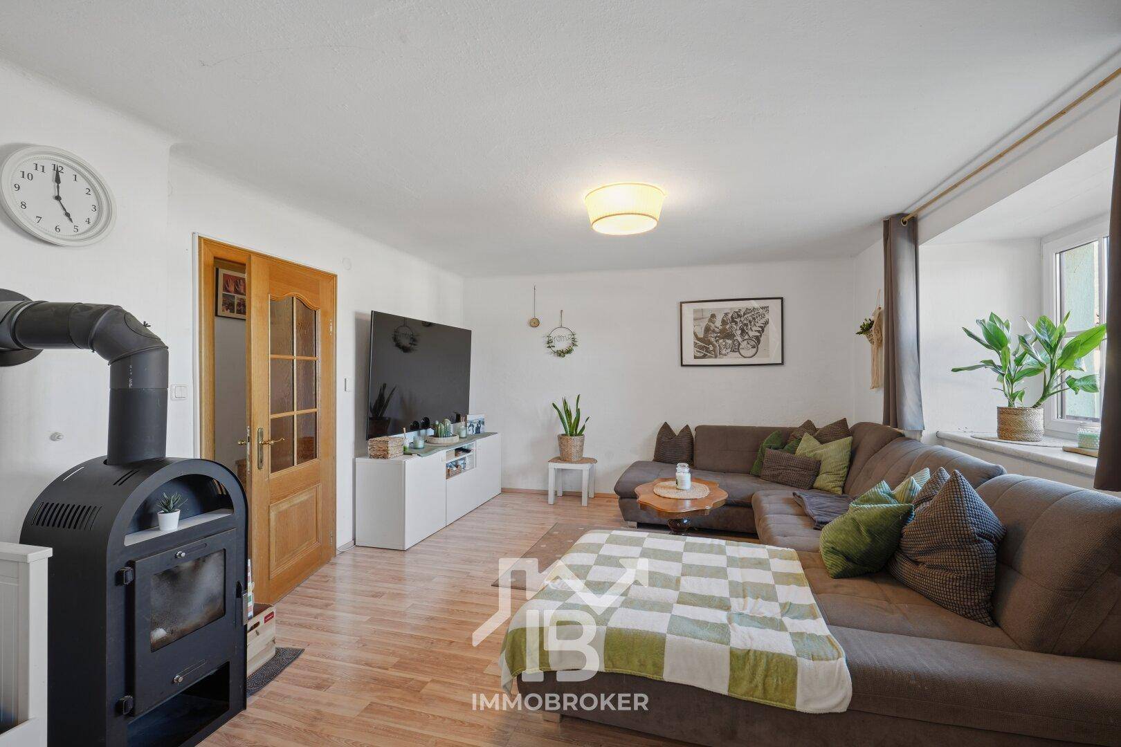 Helles Wohnzimmer mit Kaminofen, Holzboden und bequemer Sitzecke, ideal für entspannte Stunden.