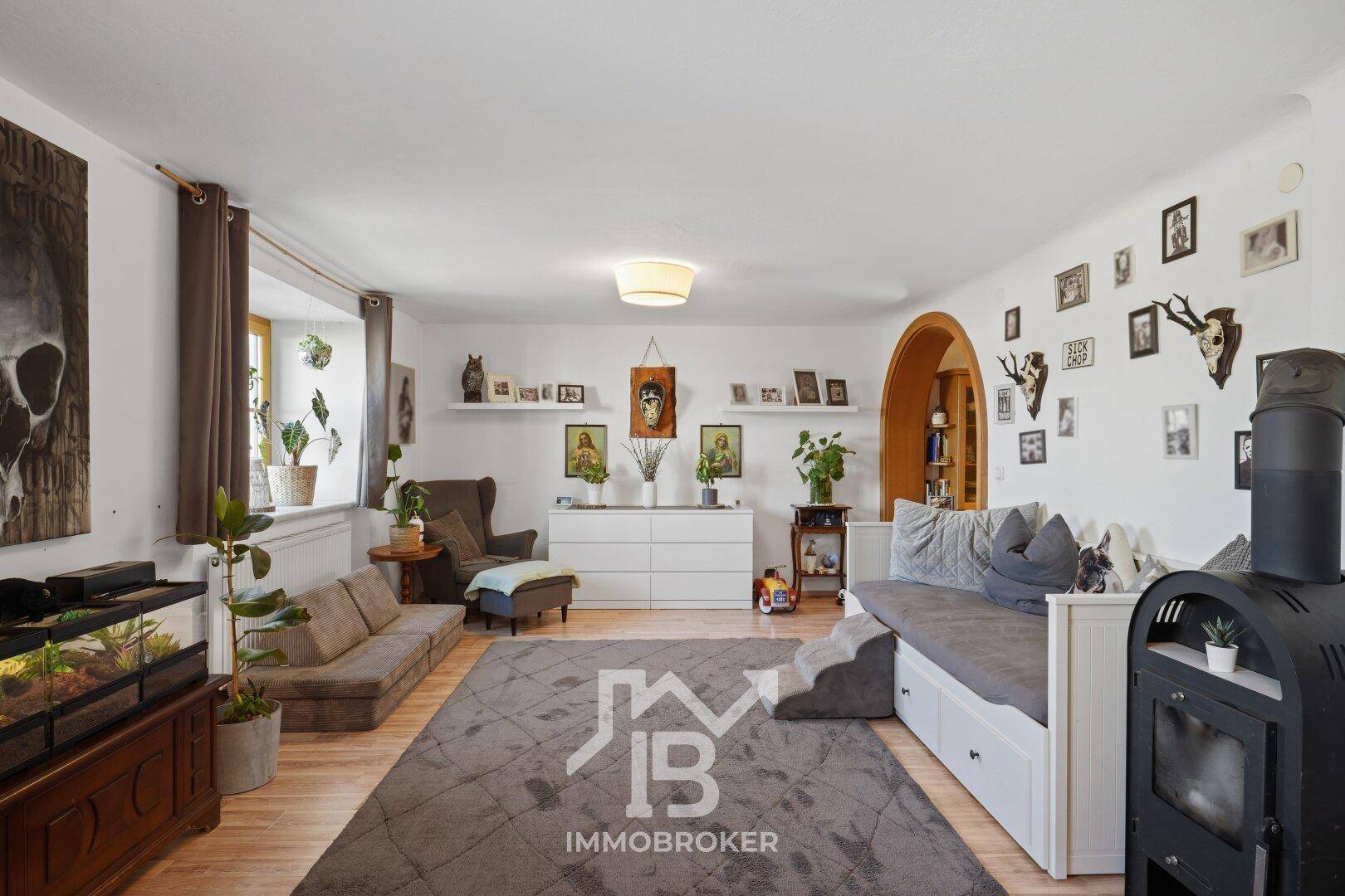 Großzügiges Wohnzimmer mit Holzboden, verschiedenen Sitzbereichen und rustikalen Dekorationselementen.