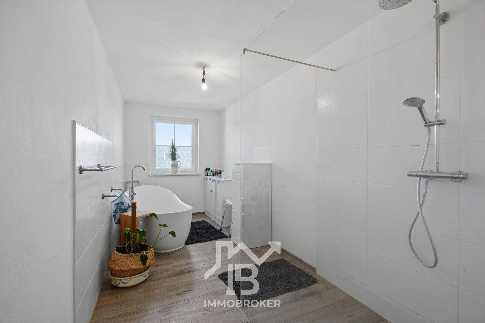 Modernes Badezimmer mit freistehender Badewanne, großer begehbarer Dusche und Fenster.