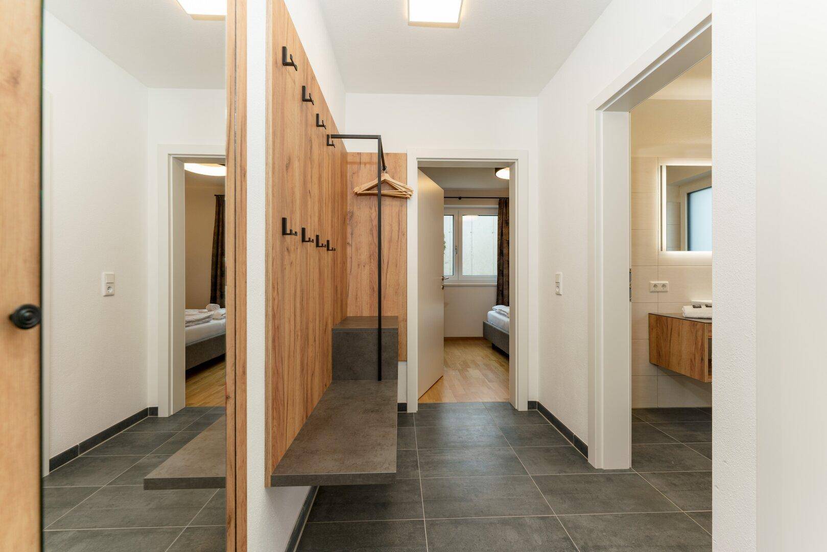Heller Flur mit Garderobe, Spiegel und Zugang zu den Schlafzimmern und Bädern.