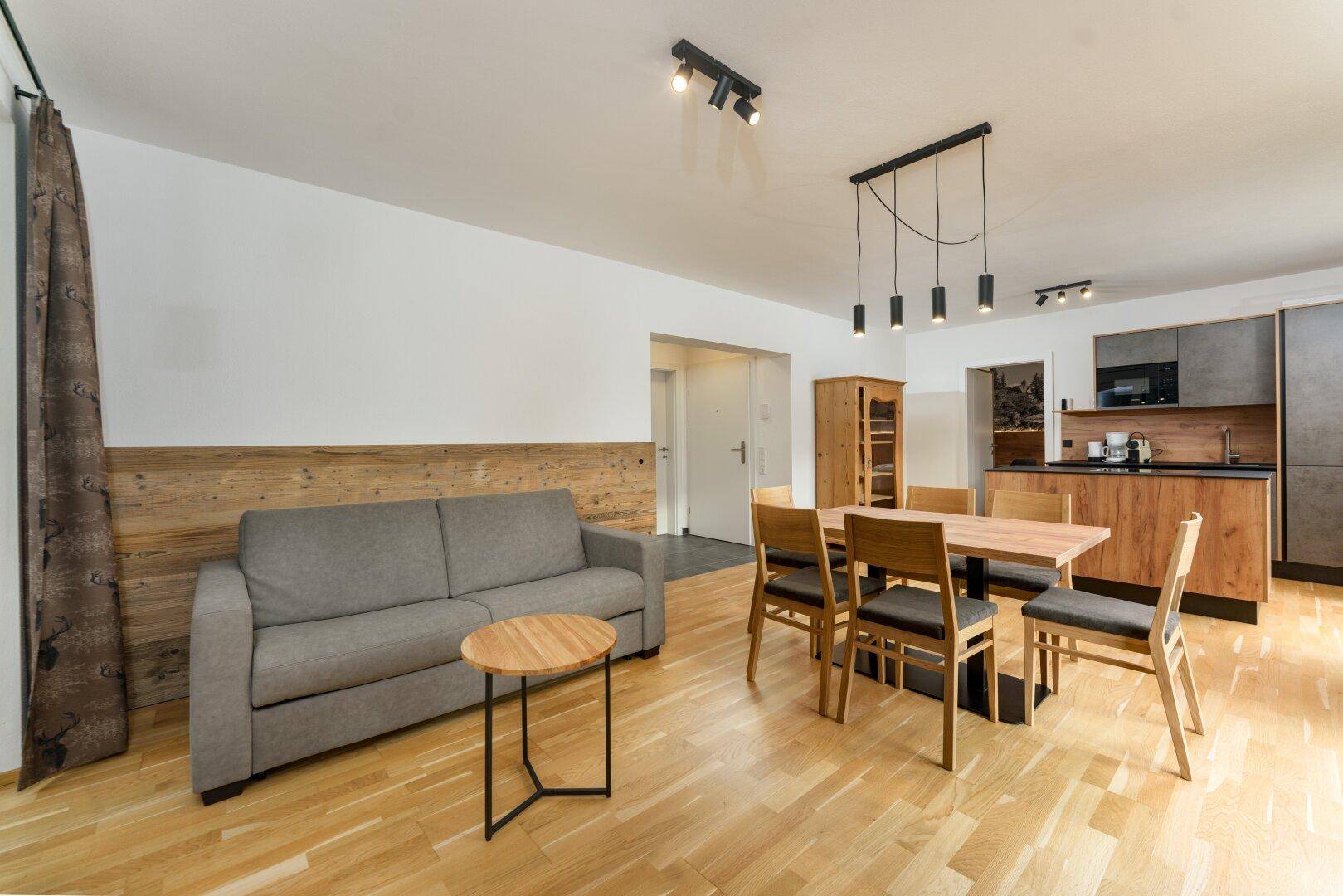 Gemütlicher Wohn-Essbereich mit Sofa, Esstisch und integrierter Küche in modernem Design.