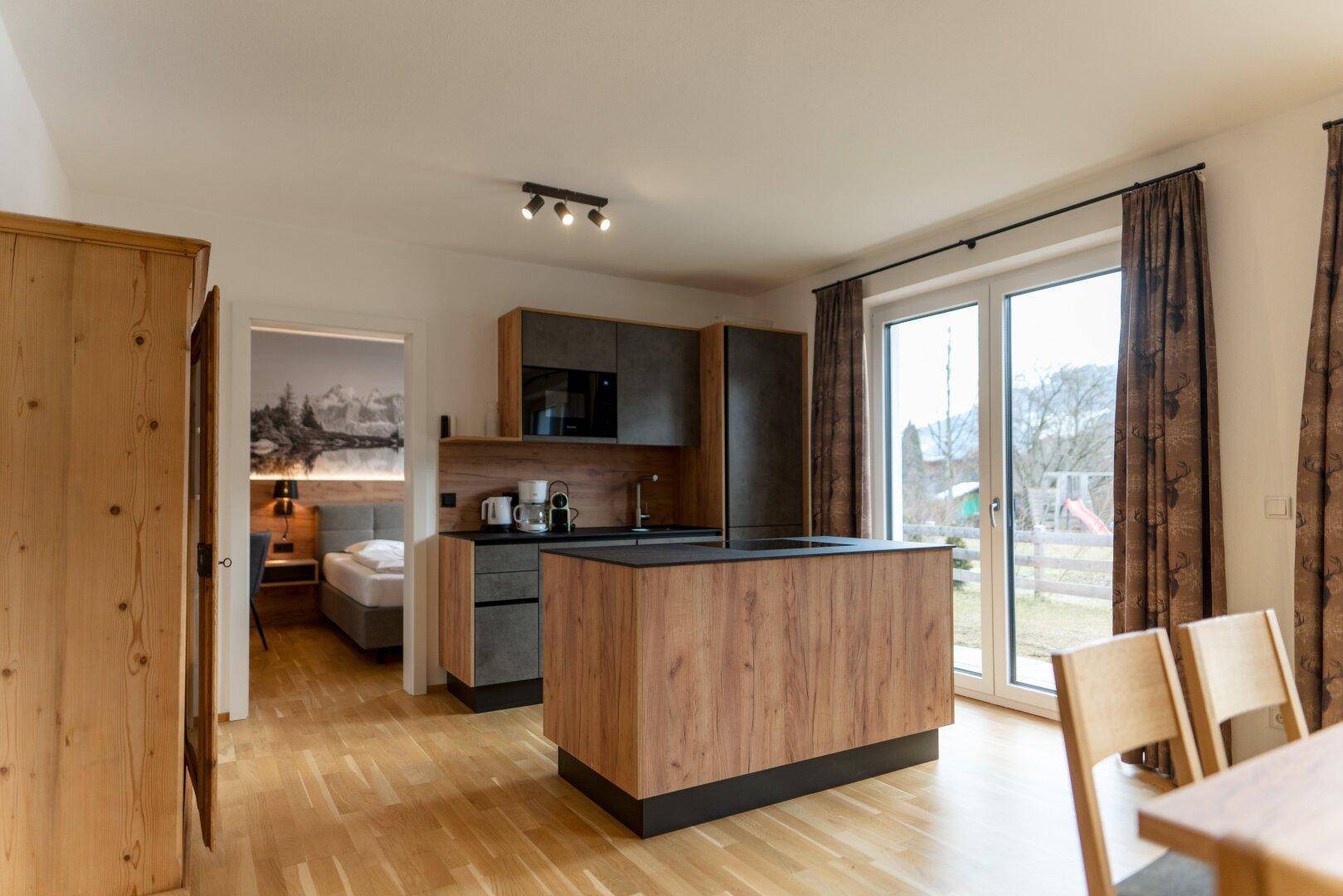 Offene Küche mit Essbereich und Blick auf den Garten, angrenzend an ein Schlafzimmer.