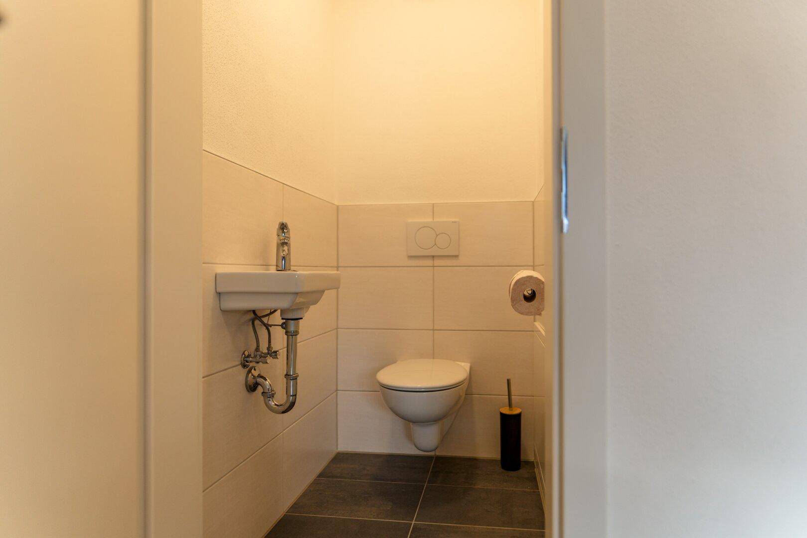 Kleines Gäste-WC mit Wand-WC und Handwaschbecken in schlichtem Design.