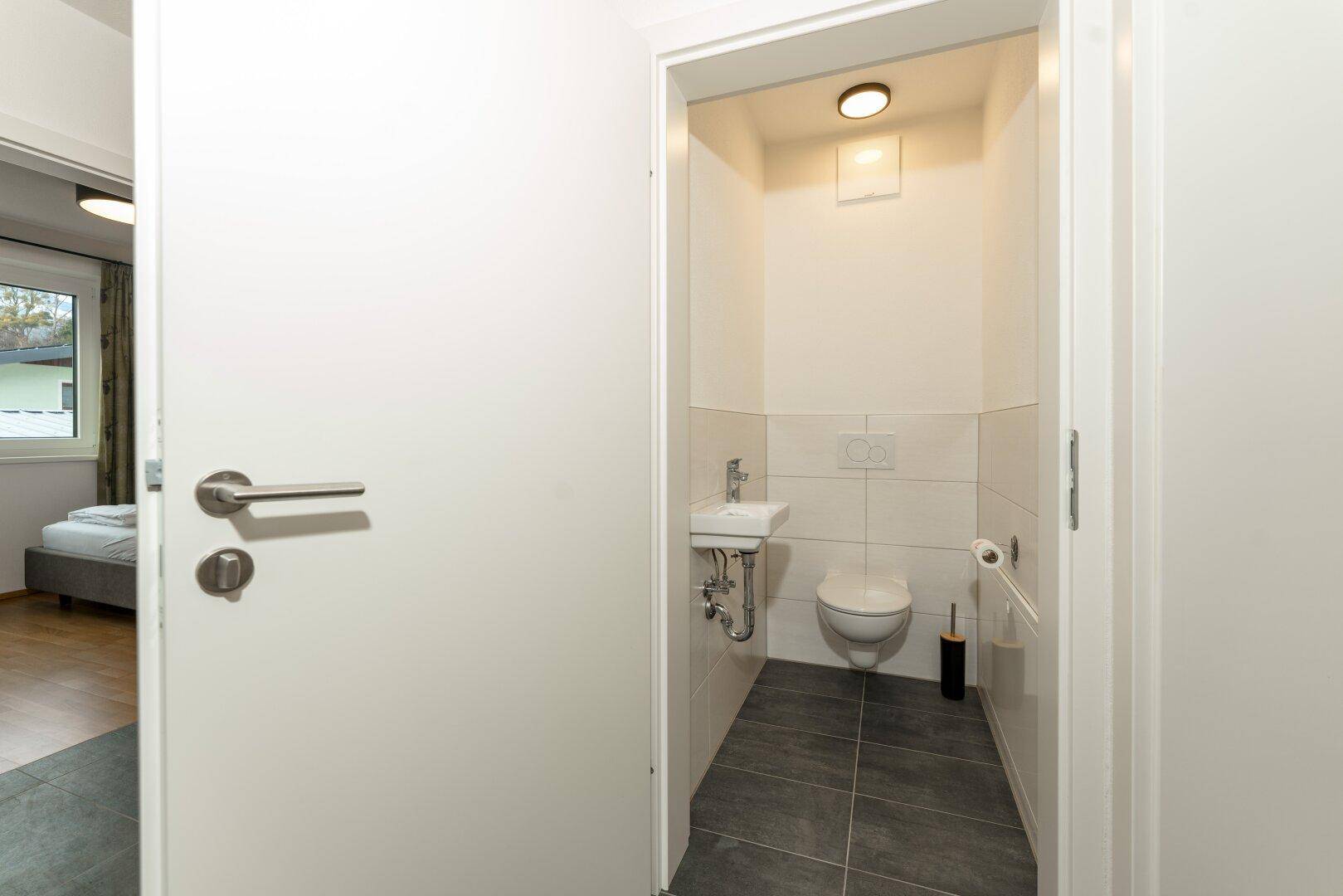 Kleines Gäste-WC mit wandhängender Toilette und Handwaschbecken, praktisch und funktional.