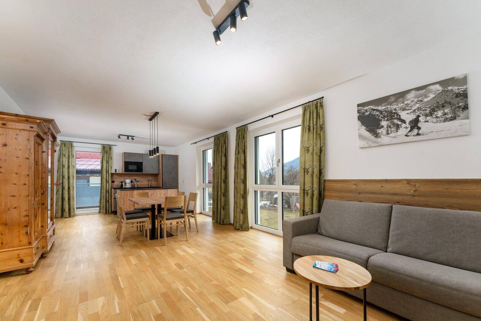 Gemütlicher Wohnbereich mit Sofa und Blick auf den Essbereich sowie die moderne Küche, umgeben von Natur.