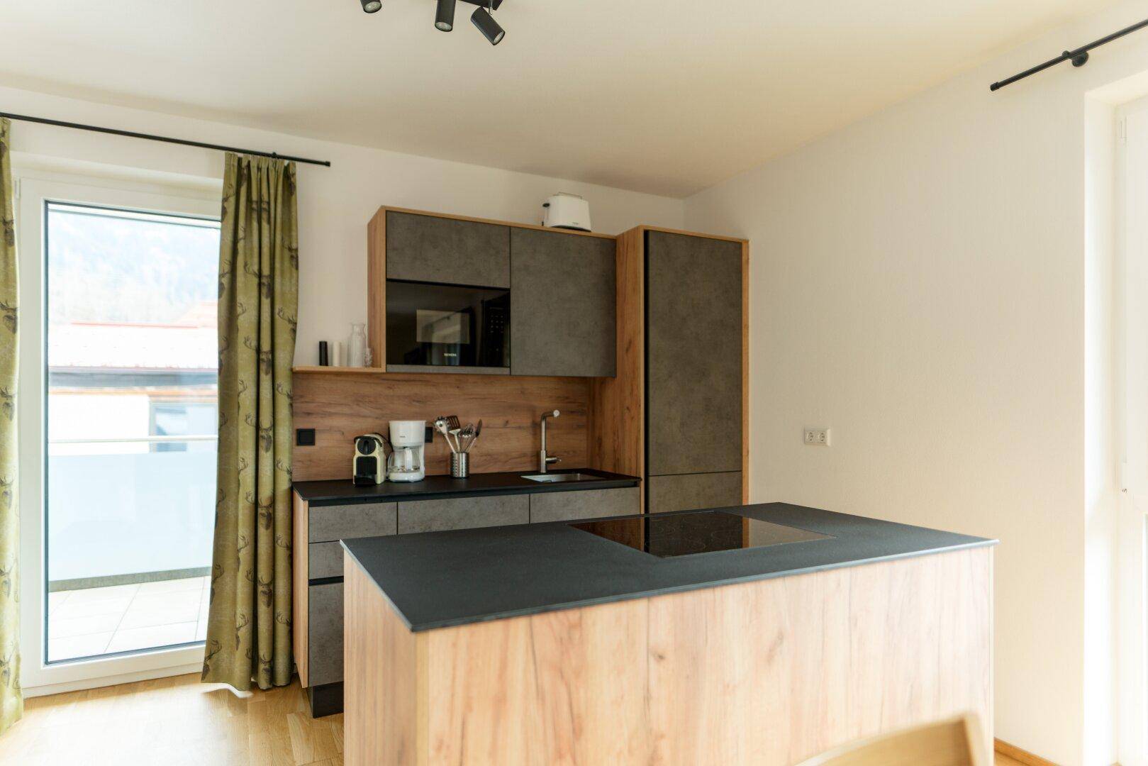 Moderne Einbauküche mit Kücheninsel, integrierten Geräten und direktem Zugang zum Balkon.