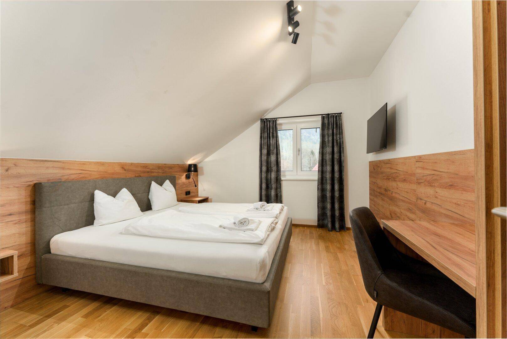 Gemütliches Schlafzimmer mit Doppelbett, Schreibtisch und Fenster mit Bergblick.
