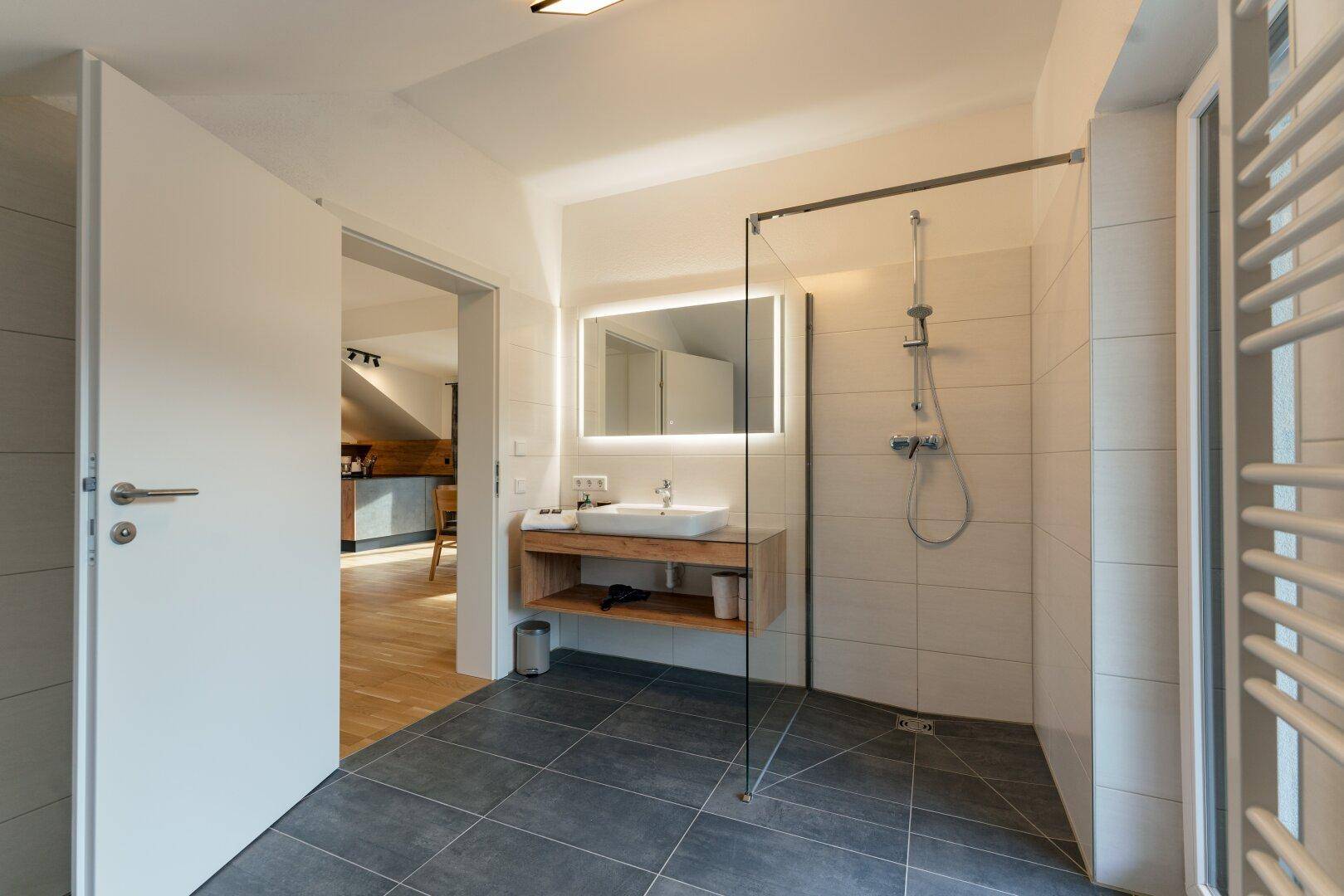 Modernes Badezimmer mit ebenerdiger Dusche, stilvollem Waschtisch und beheiztem Handtuchhalter.