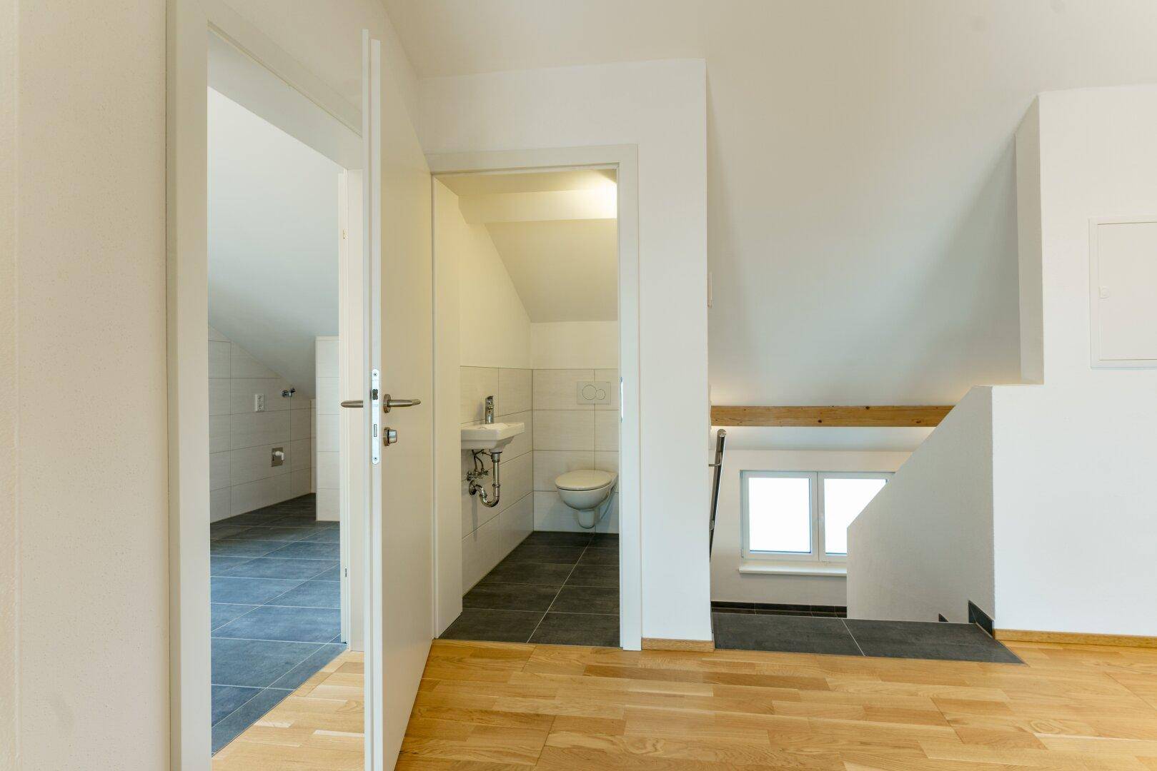 Heller Flurbereich mit Zugang zur Gästetoilette und Blick auf die untere Etage.