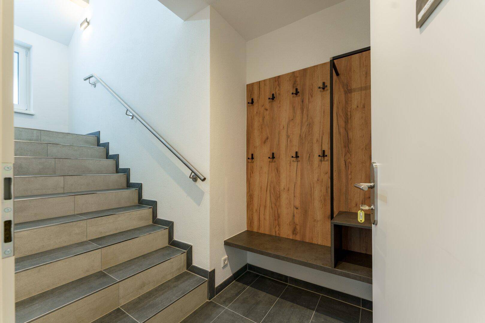 Heller Eingangsbereich mit Garderobe und Treppe, die in die oberen Stockwerke führt.