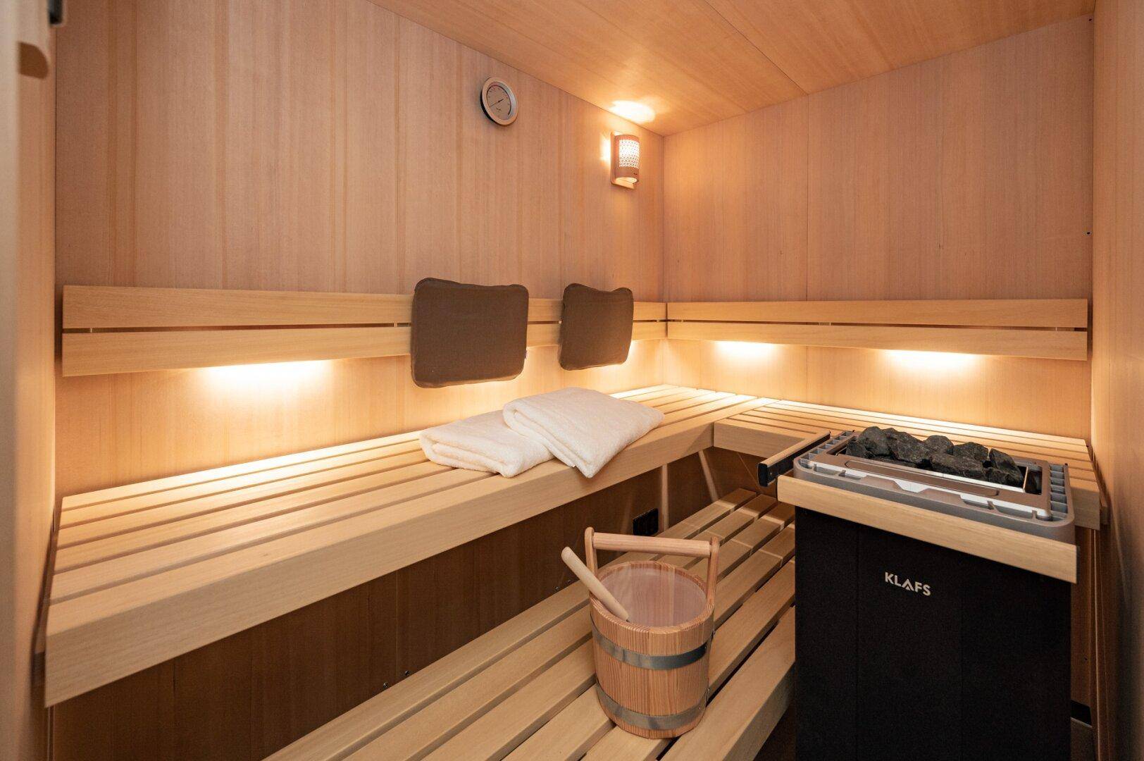 Moderne Holzsauna mit bequemen Bänken und traditionellem Saunaofen für Entspannung.