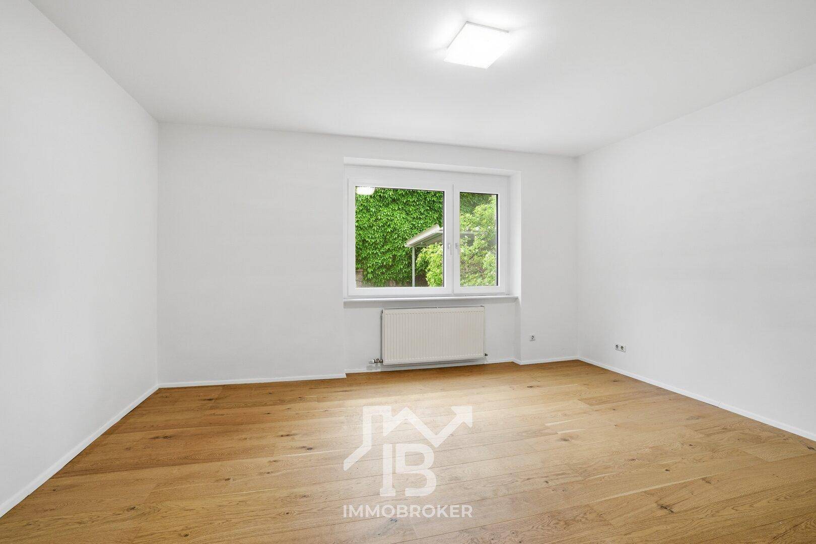 Freundliches Zimmer mit Parkettboden und Fenster, das viel Tageslicht hereinlässt.