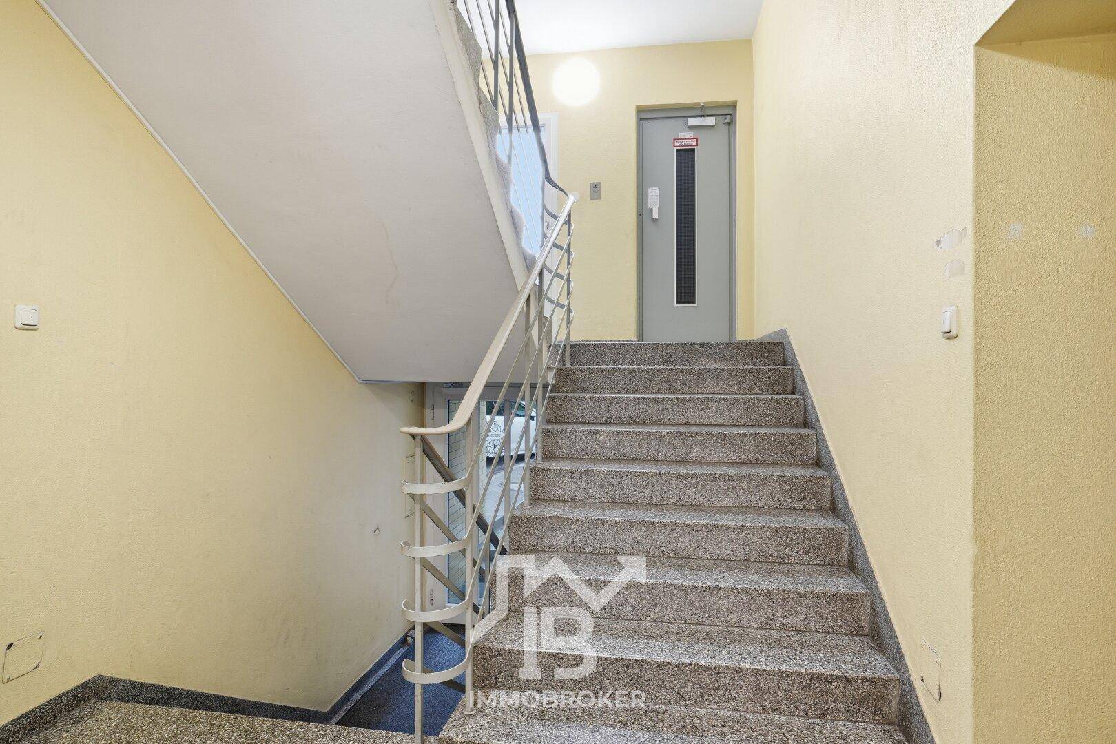 Treppenhaus mit Granitstufen und Geländer, das zu den oberen Etagen führt.