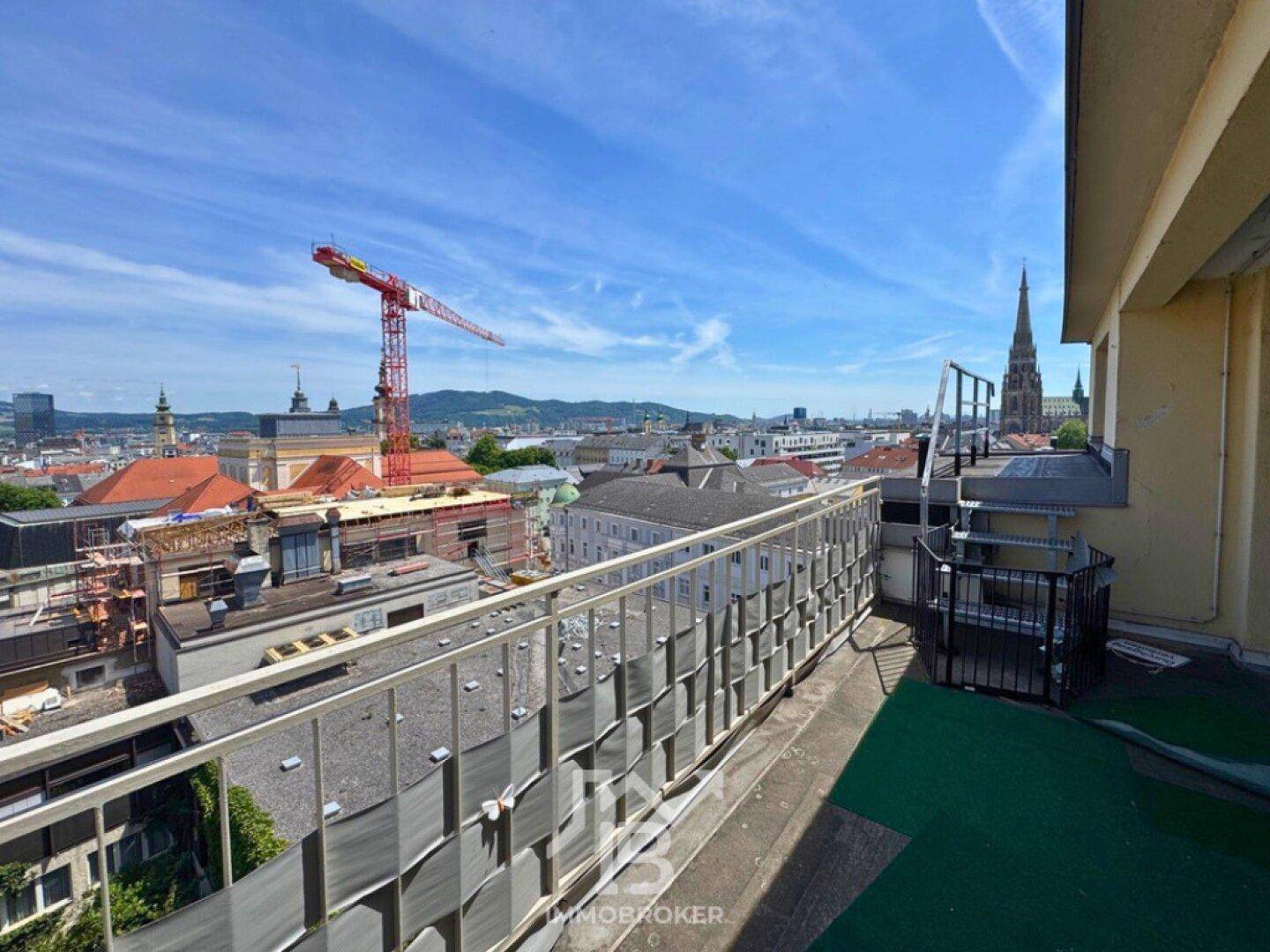 Weitläufige Dachterrasse mit Panoramablick über die Stadt und die Berge im Hintergrund.