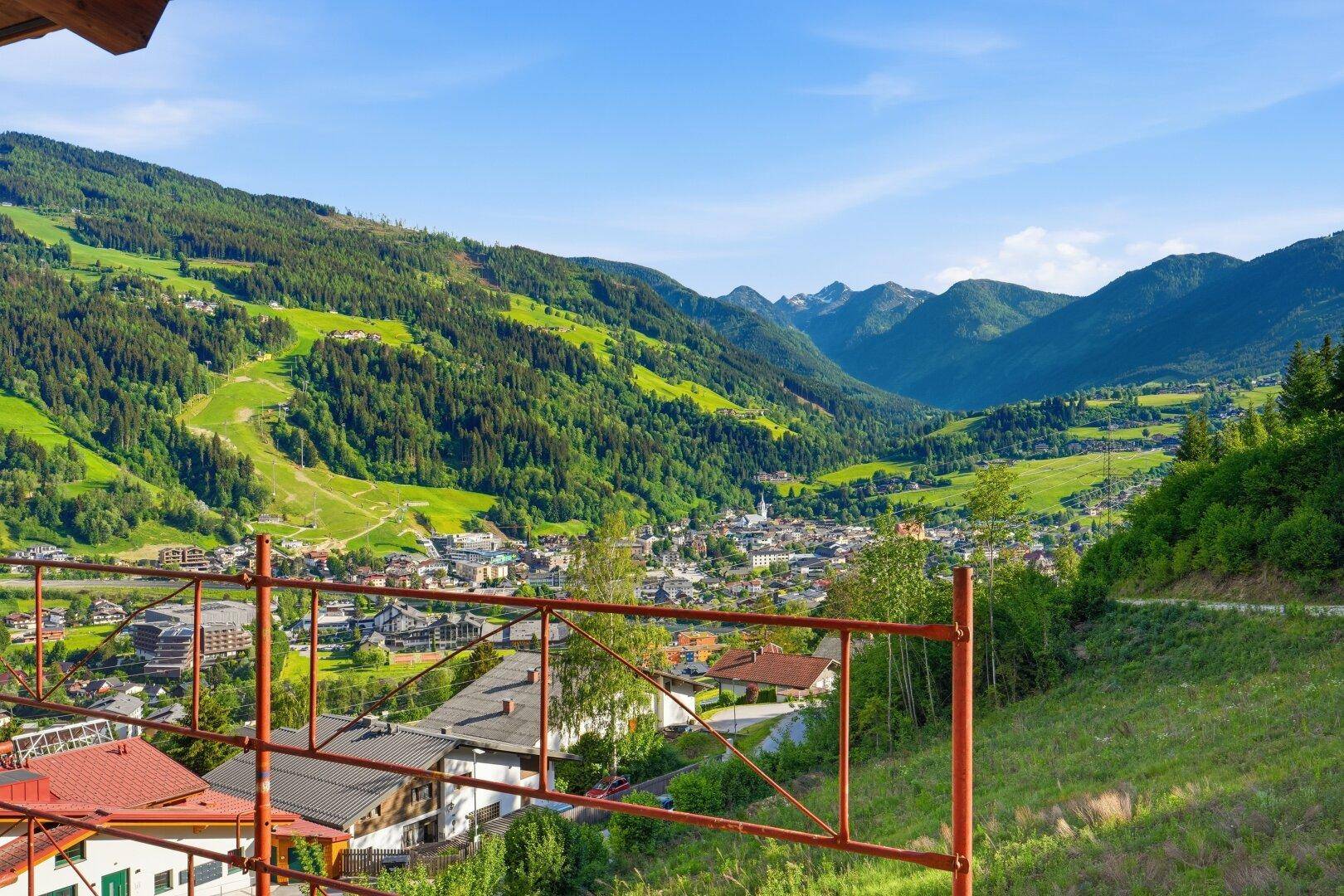 Panoramablick von einem Balkon auf die grüne Berglandschaft und das malerische Tal mit der Stadt.