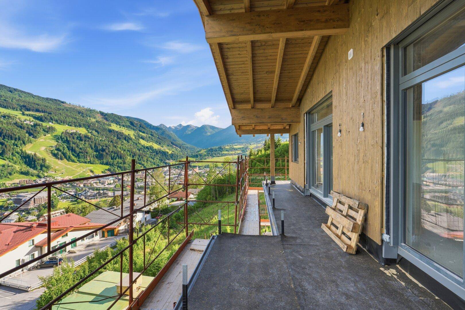 Unfertiger Balkon mit Gerüst und weitem Blick auf die grüne Berglandschaft und das Tal bei Tageslicht.