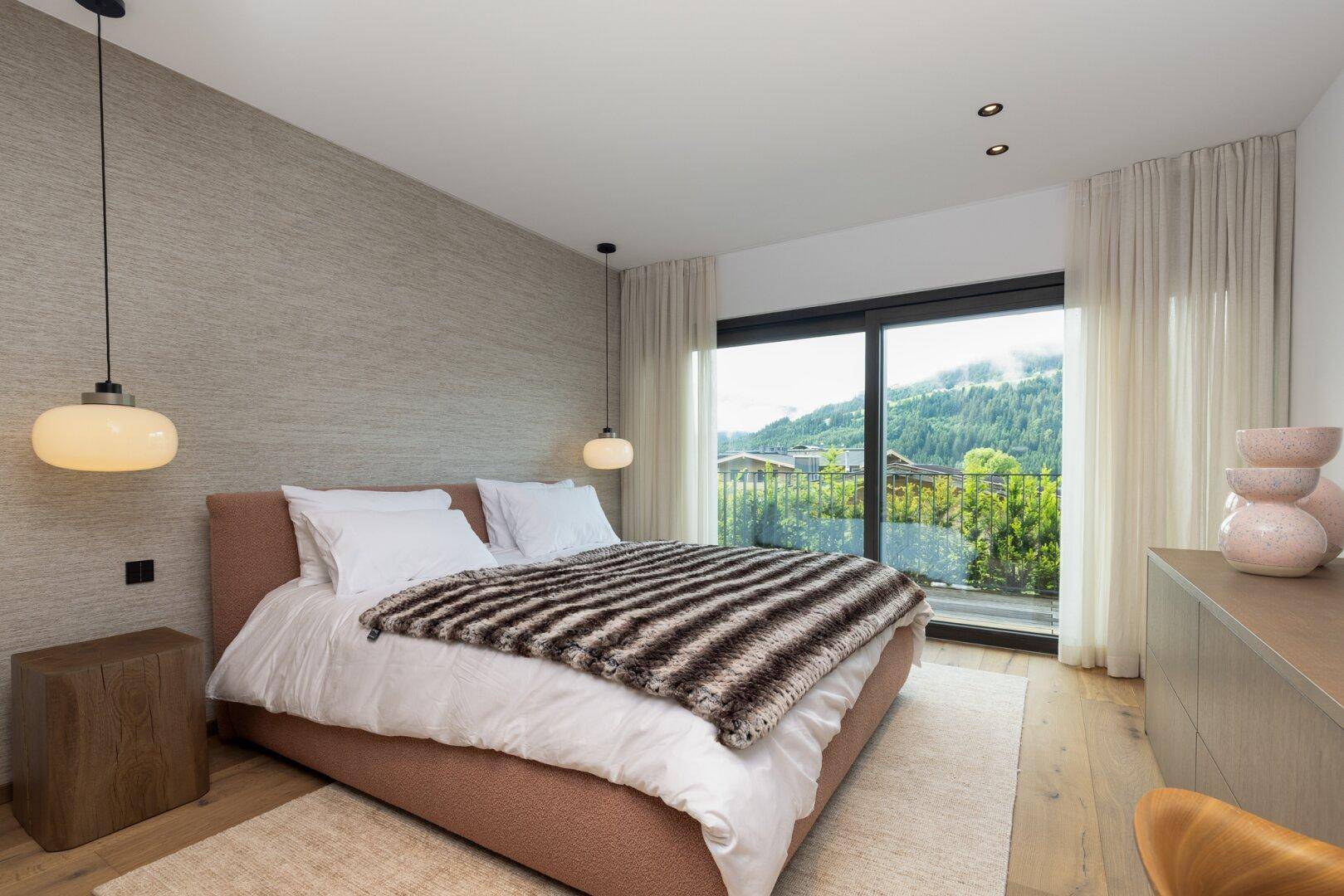 Gemütliches Schlafzimmer mit strukturierten Wänden, Holzboden und direktem Balkonzugang.