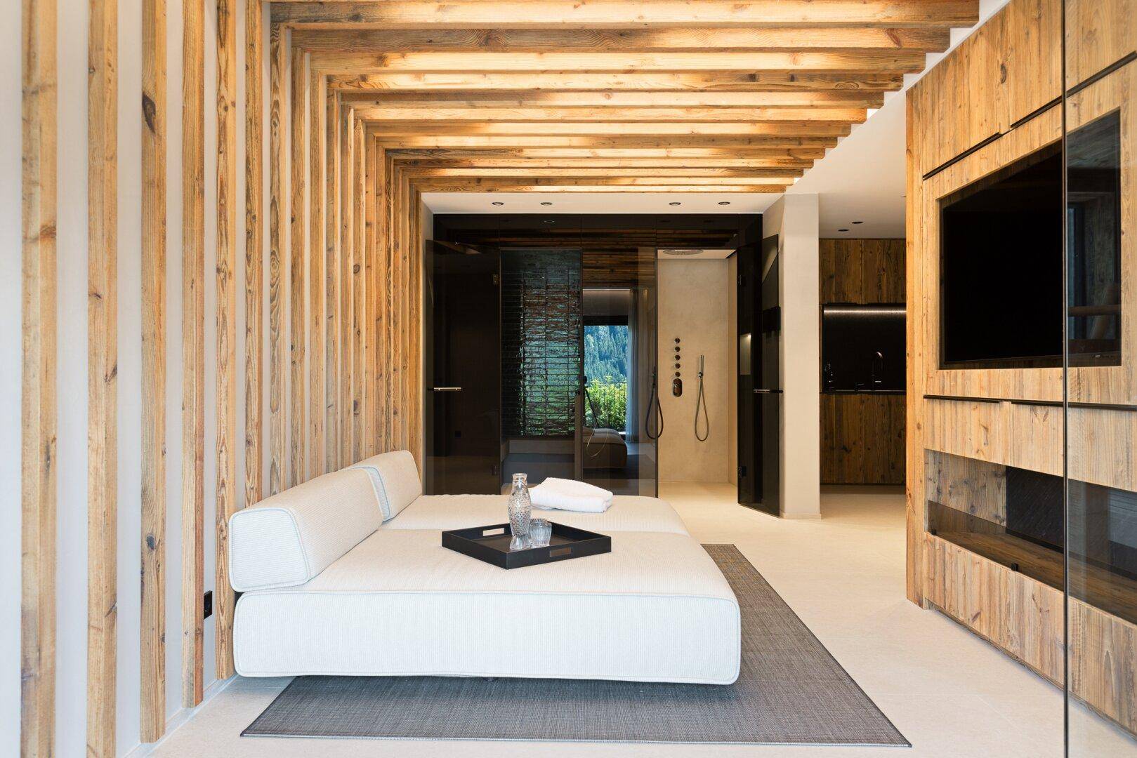 Modernes Schlafzimmer mit Holzwänden, Tagesbett und offenem Duschbereich.