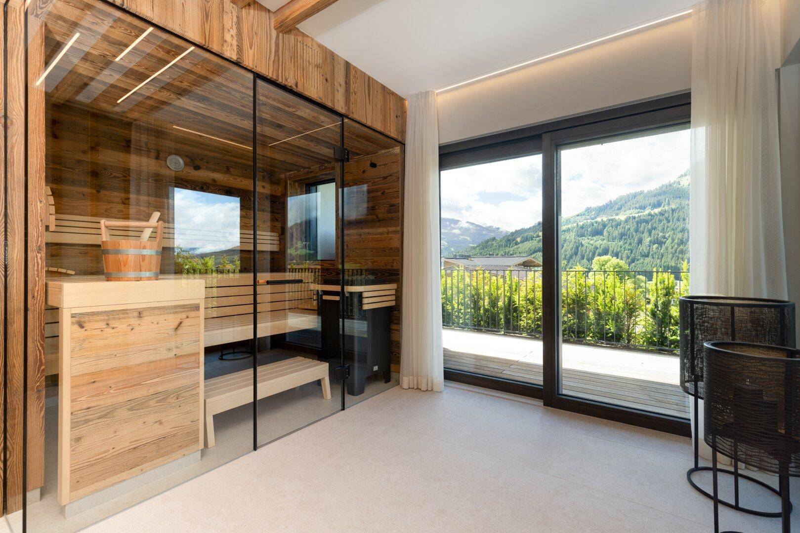 Private Sauna mit Glasfront, Holzbänken und Panoramablick auf die Berge.