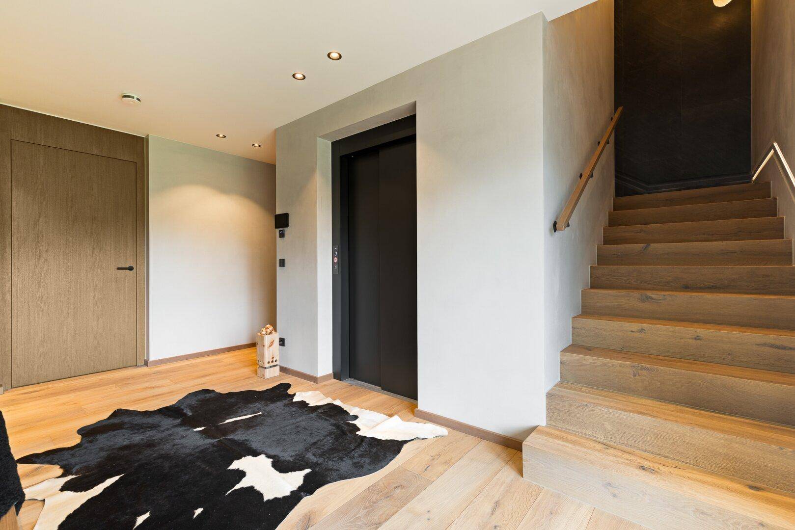 Geräumiger Flur mit Holzboden, Aufzug und Treppe zu den oberen Etagen.