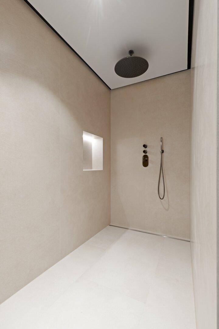 Geräumige, moderne begehbare Dusche mit Regenduschkopf und minimalistischem Design.