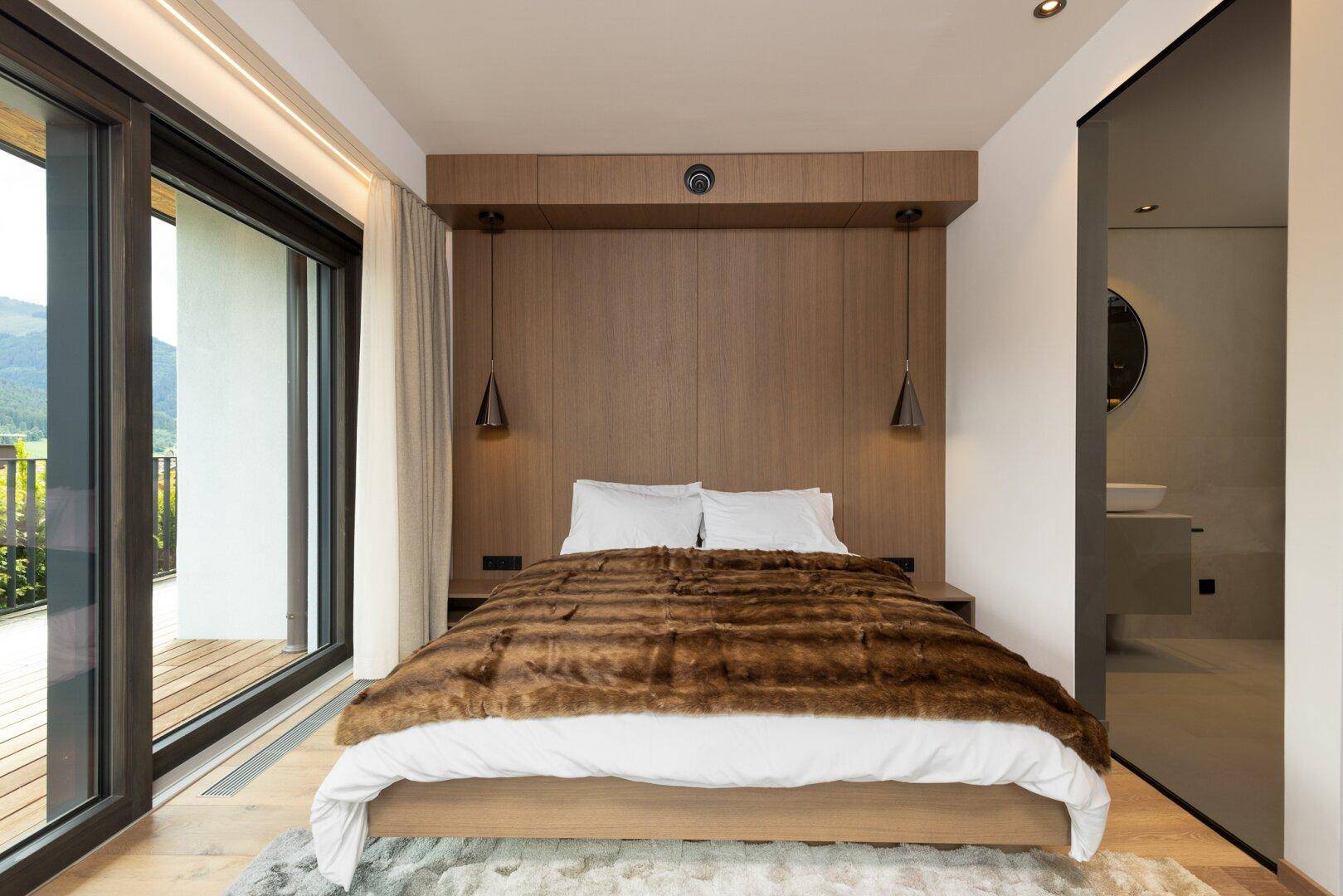 Modernes Schlafzimmer mit Holzwandverkleidung, Einbauschränken und direktem Zugang zum Badezimmer.