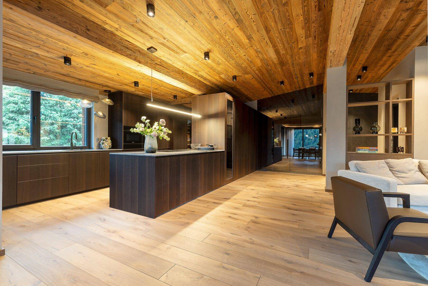 Moderne offene Küche mit dunklen Holzfronten, Kücheninsel und Holzbalkendecke.