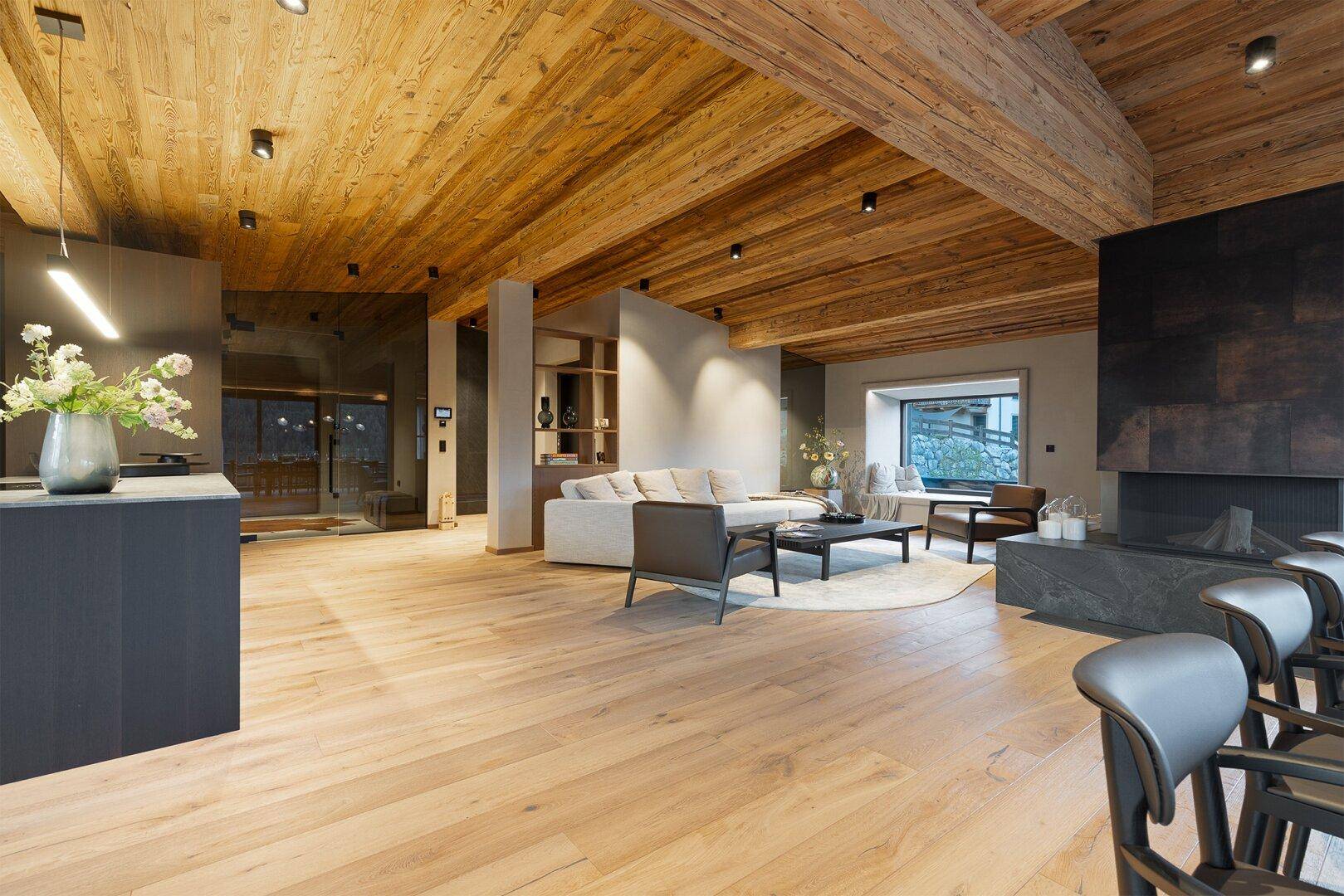 Geräumiger offener Wohnbereich mit Kamin, bequemen Sofas und Holzbalkendecke.