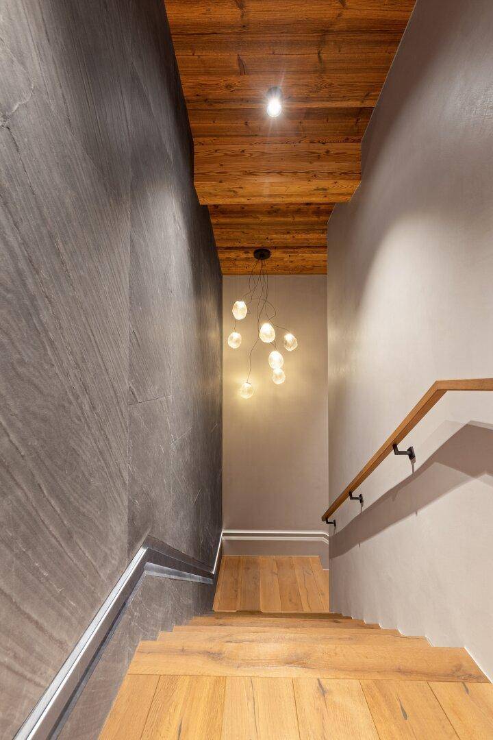 Elegantes Treppenhaus mit Holzstufen, Handlauf und moderner Beleuchtung.