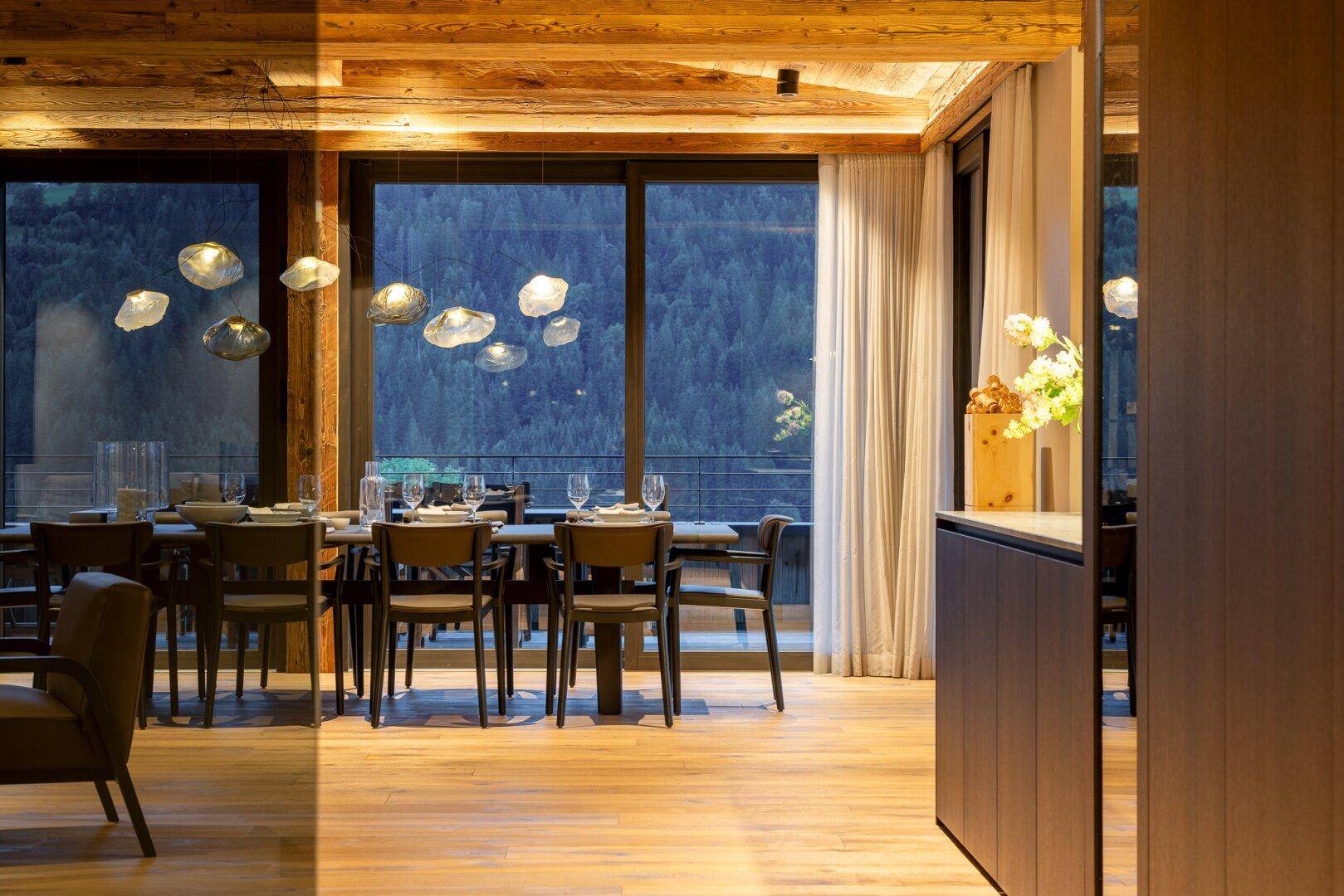 Eleganter Essbereich mit moderner Beleuchtung und Panoramablick auf die dunklen Berge.
