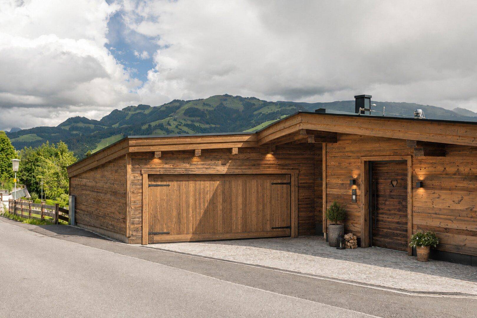 Geräumige Holzgarage mit breitem Tor und Stellplatz, eingebettet in die Berglandschaft.