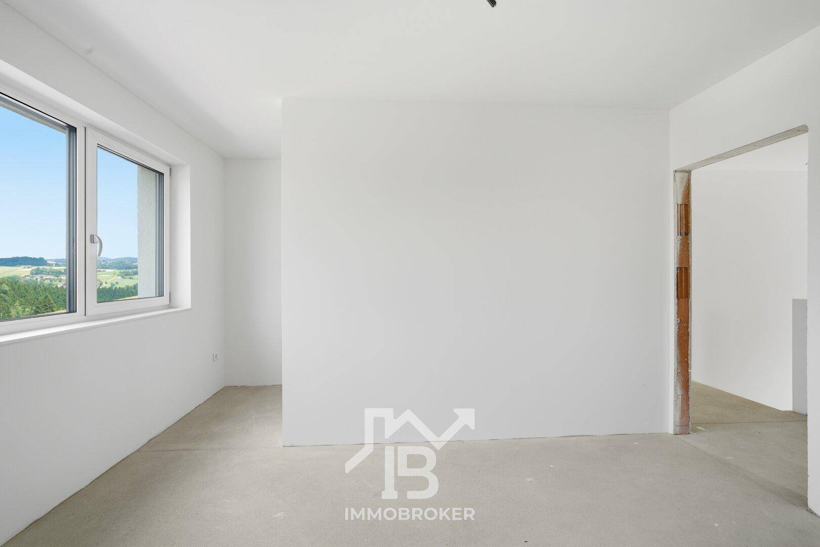 Unfertiger Raum mit Betonboden und offenem Durchgang, bereit für den Innenausbau.