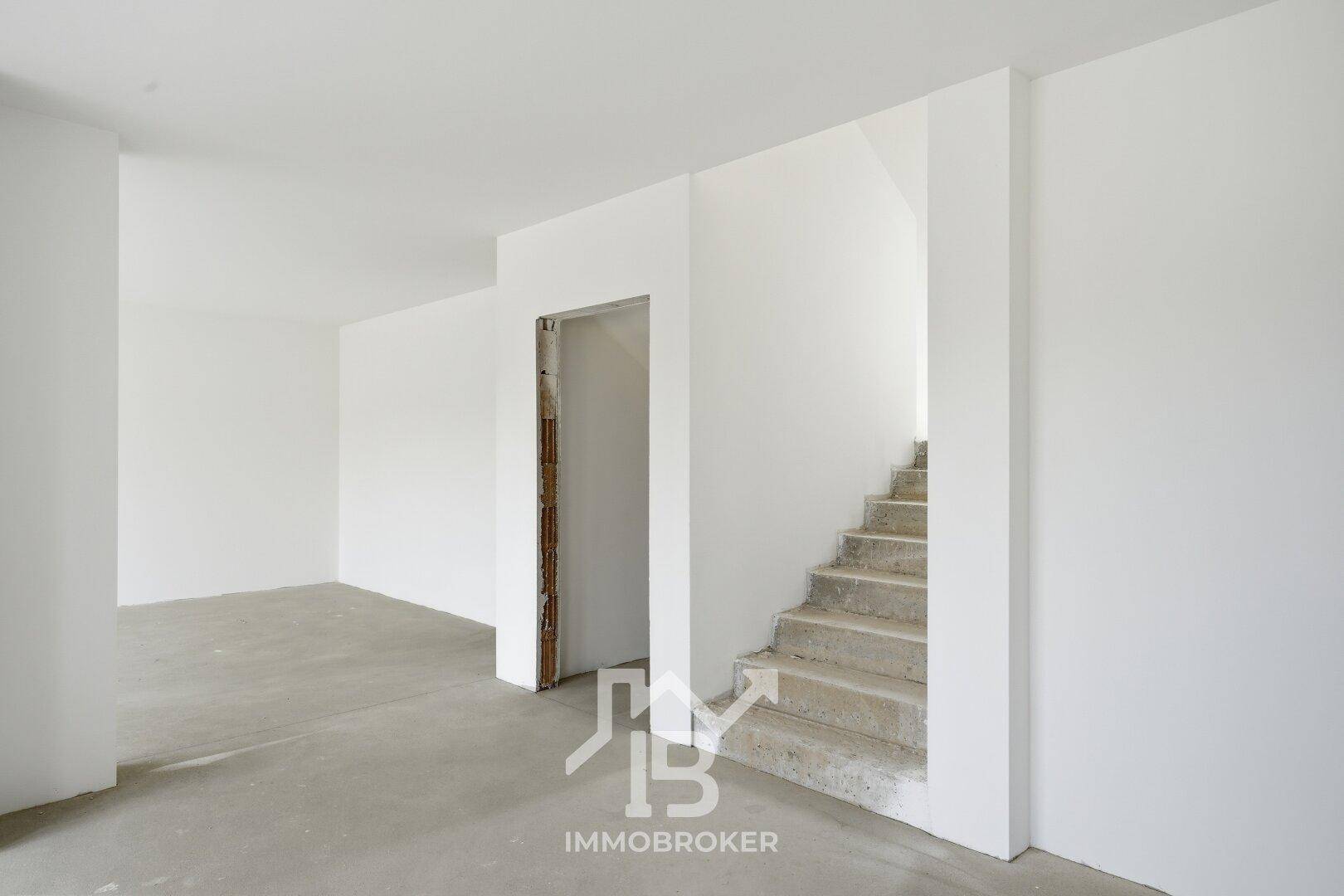 Unfertiger Flur mit Betontreppe und Rohbauwänden, bereit für den weiteren Ausbau.