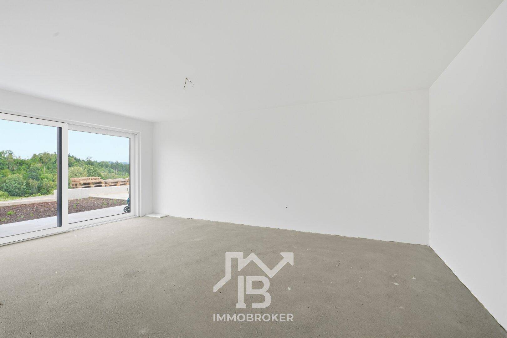 Heller Raum im Rohbauzustand mit großen Schiebetüren und Blick ins Freie.