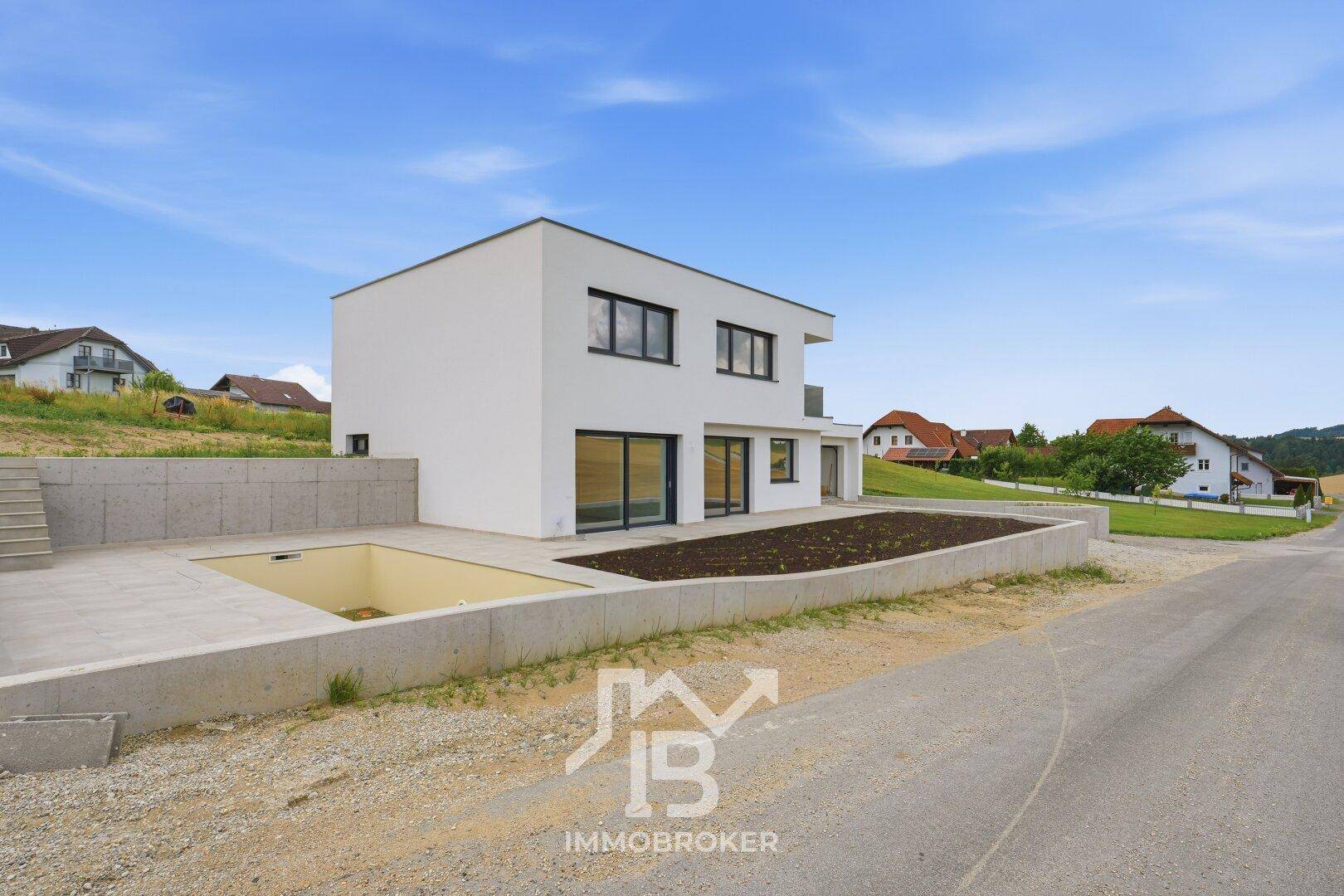 Modernes Einfamilienhaus im Bau mit vorbereitetem Poolbereich und unfertiger Gartenfläche.
