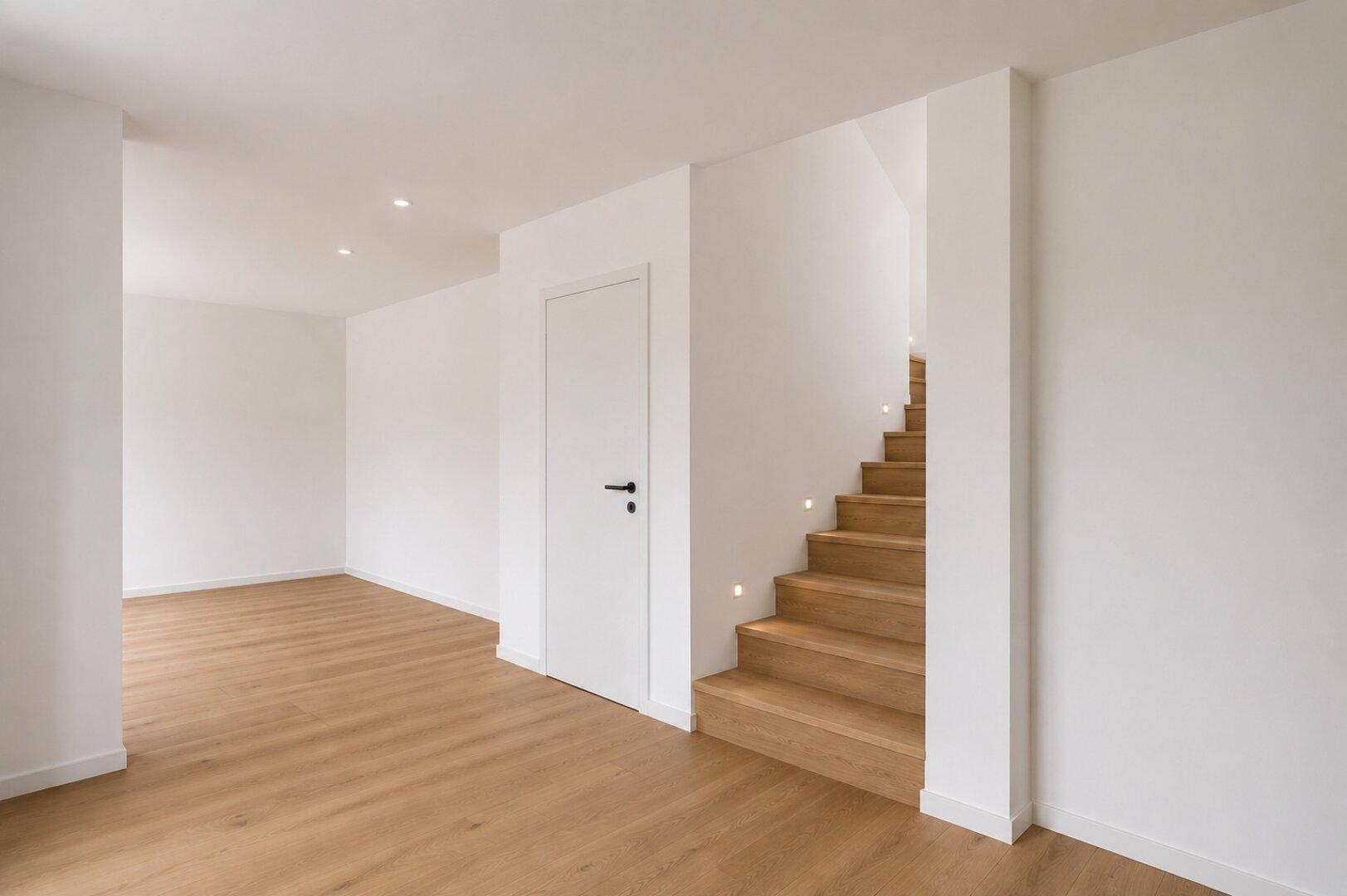 Heller Flur mit Holztreppe und modernem Holzfußboden in einem Neubau.