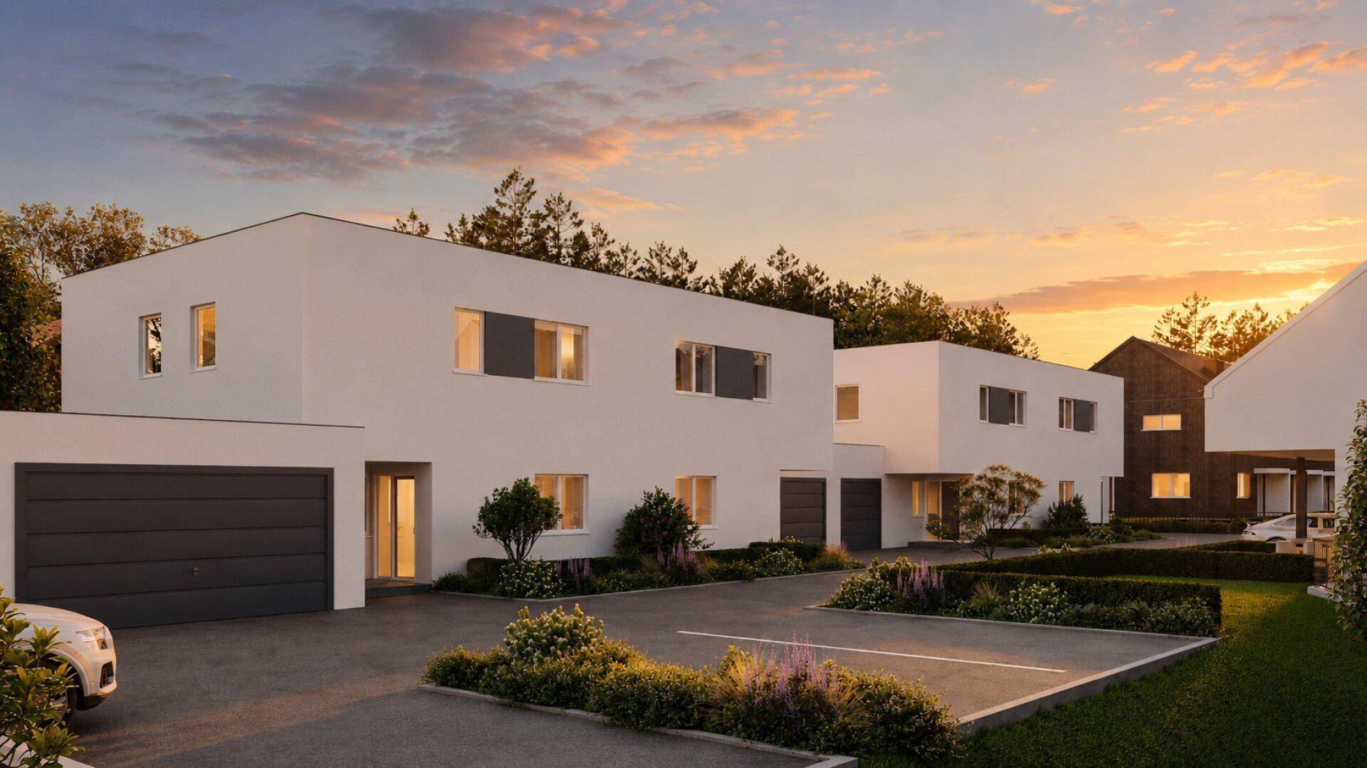 Reihenhäuser mit moderner Architektur, Garagen und Außenparkplätzen bei Sonnenuntergang.