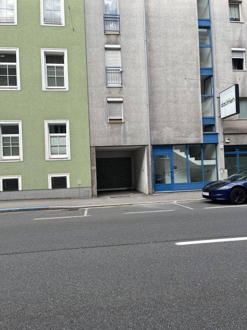 Fassade eines modernen Gebäudes mit grünen und grauen Abschnitten an einer Stadtstraße.