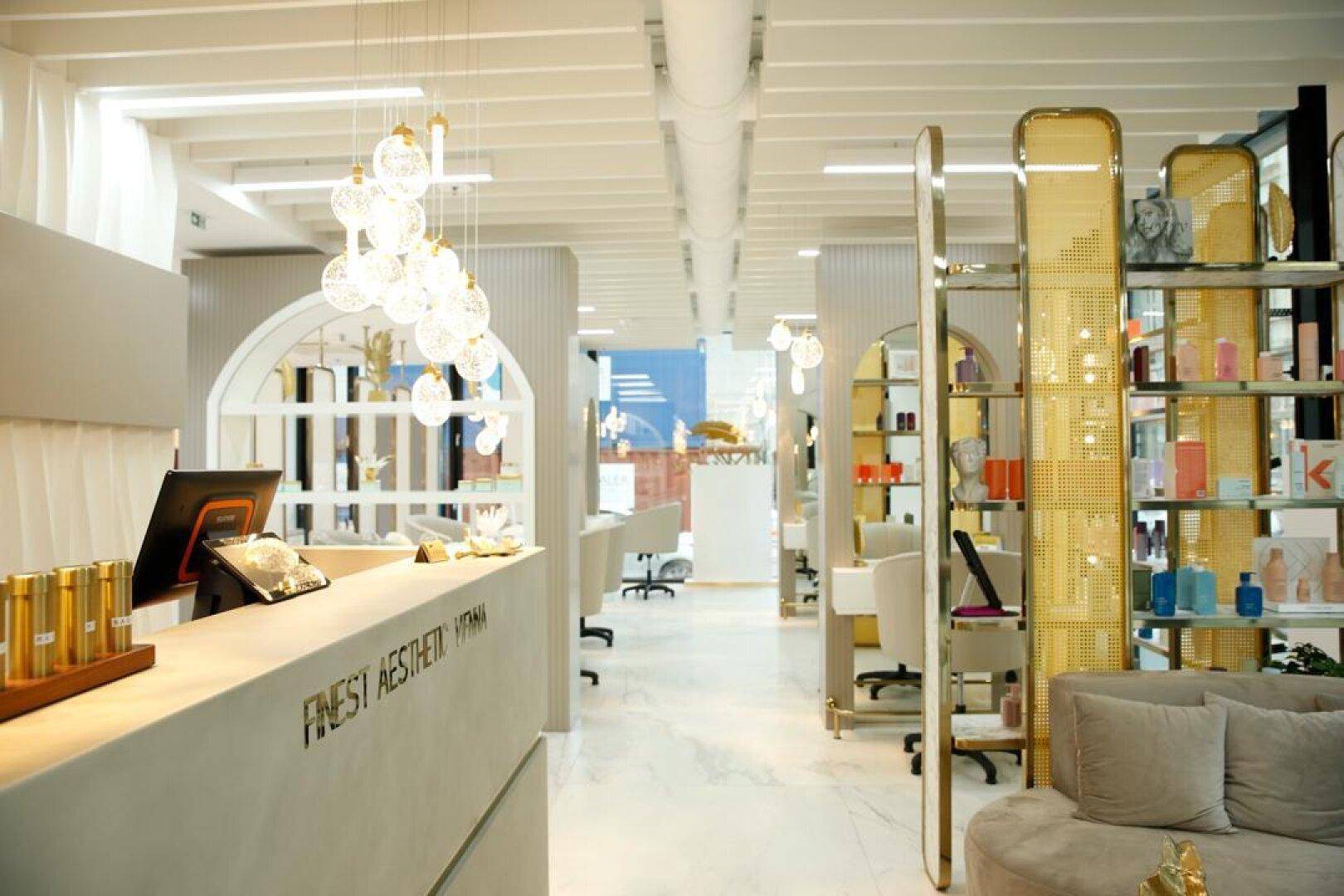 Geräumiger Empfangs- und Behandlungsbereich mit stilvoller Einrichtung, Produktregalen und modernen Leuchten.