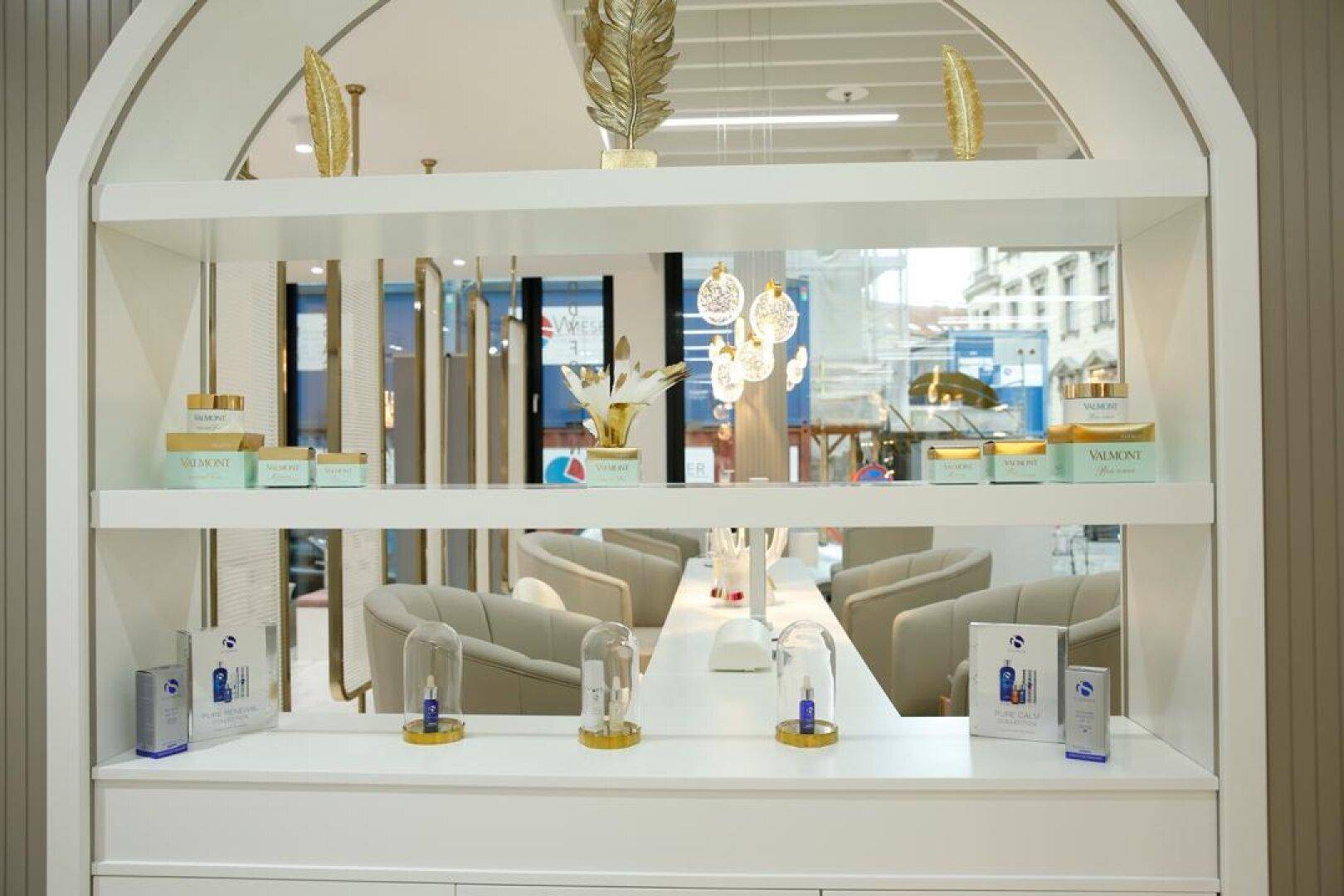Nahaufnahme eines eleganten Produktregals mit verschiedenen Kosmetikartikeln und goldenen Dekorationen.