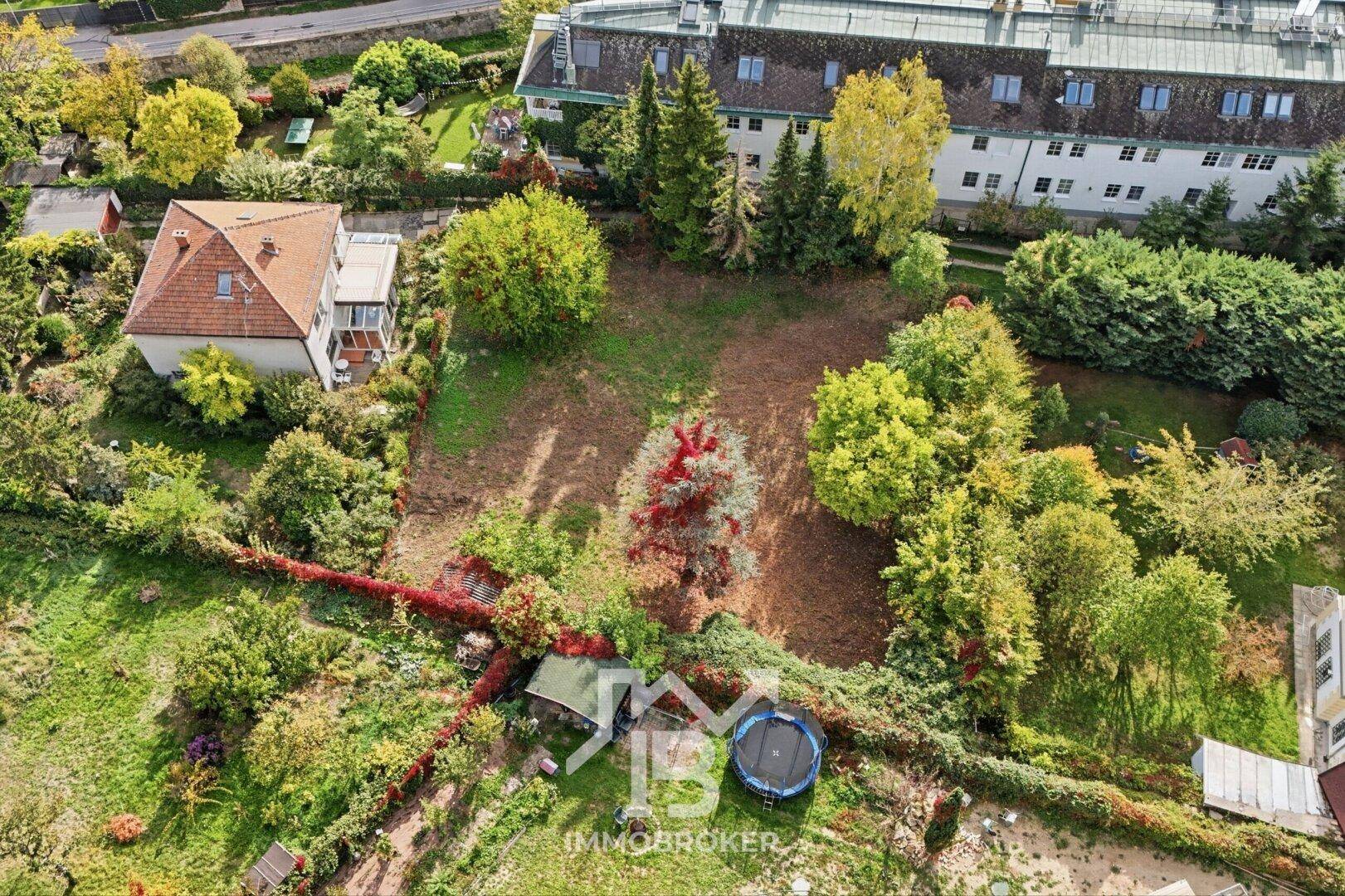 Unbebautes Grundstück mit Bäumen und Sträuchern, umgeben von weiteren Wohnhäusern.