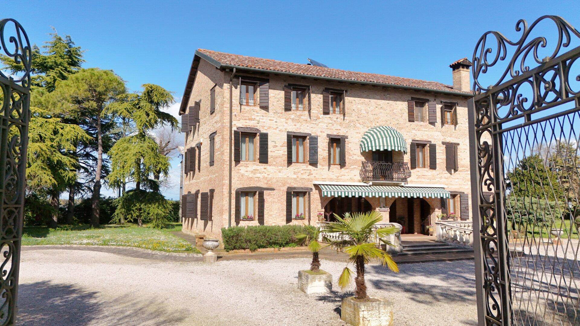 Historisches Anwesen mit schmiedeeisernem Tor, Ziegelfassade und gepflegtem Vorgarten.