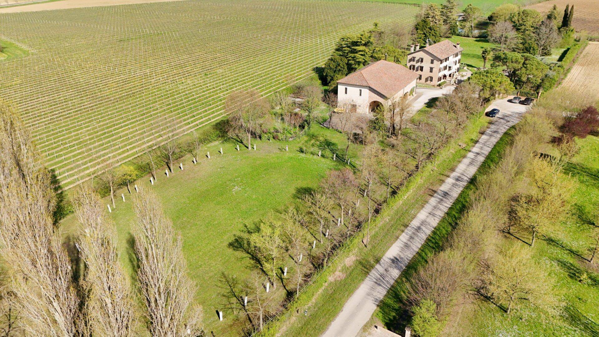 Luftaufnahme des Anwesens mit umliegenden Weinbergen und weiten Feldern unter blauem Himmel.