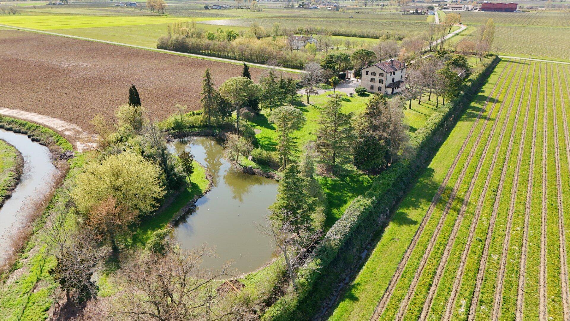 Luftaufnahme des Anwesens mit Teich, umgeben von Weinbergen und grünen Feldern.