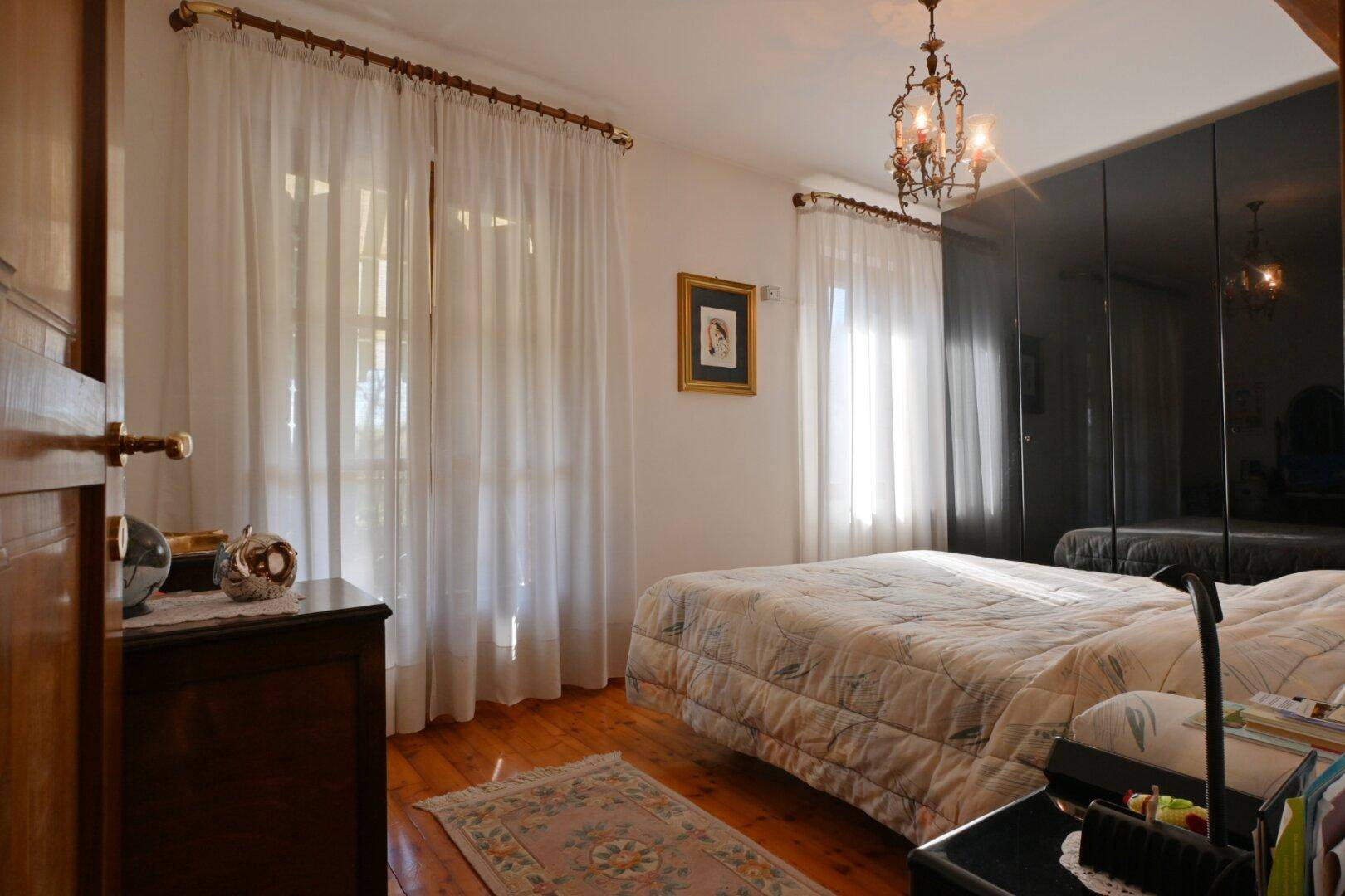 Schlafzimmer mit Holzboden, Doppelbett und großem Spiegelschrank.