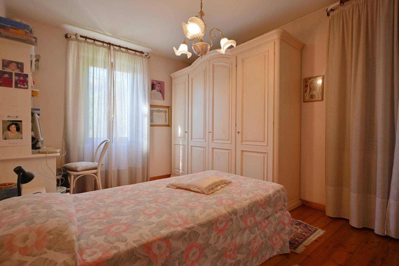 Schlafzimmer mit Holzboden, Einzelbett und großem weißen Kleiderschrank.